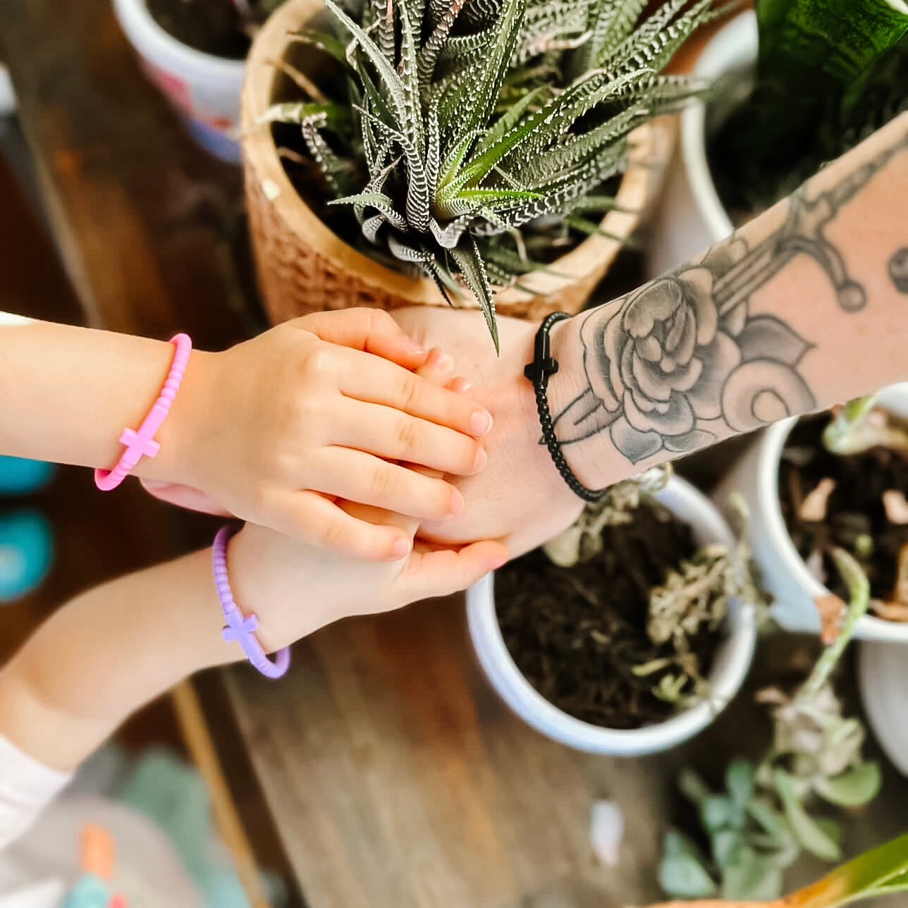 Two hands, one with tattoos and a tattooed arm, holding hands with a child&