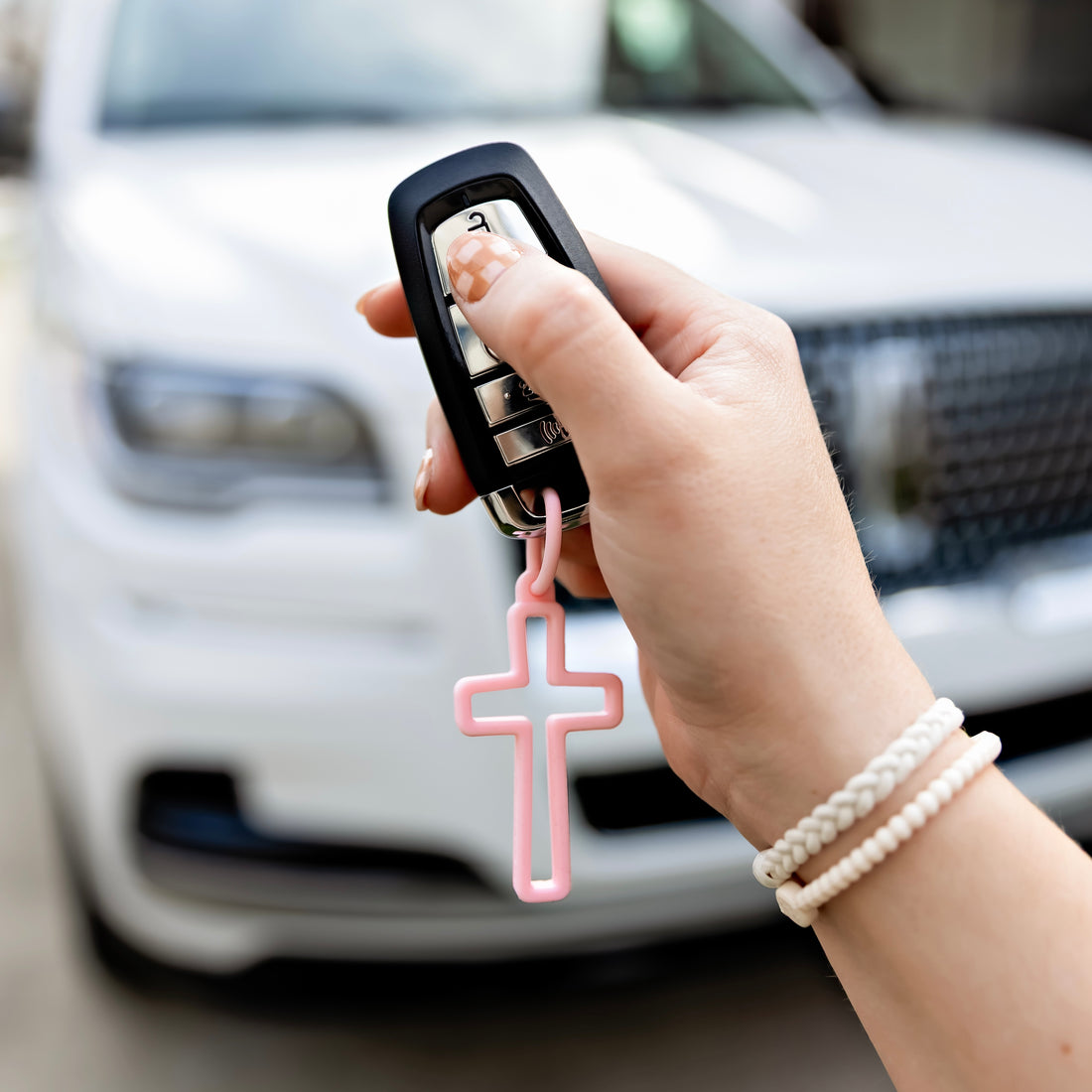 Woman holding car keys with cross charm attached