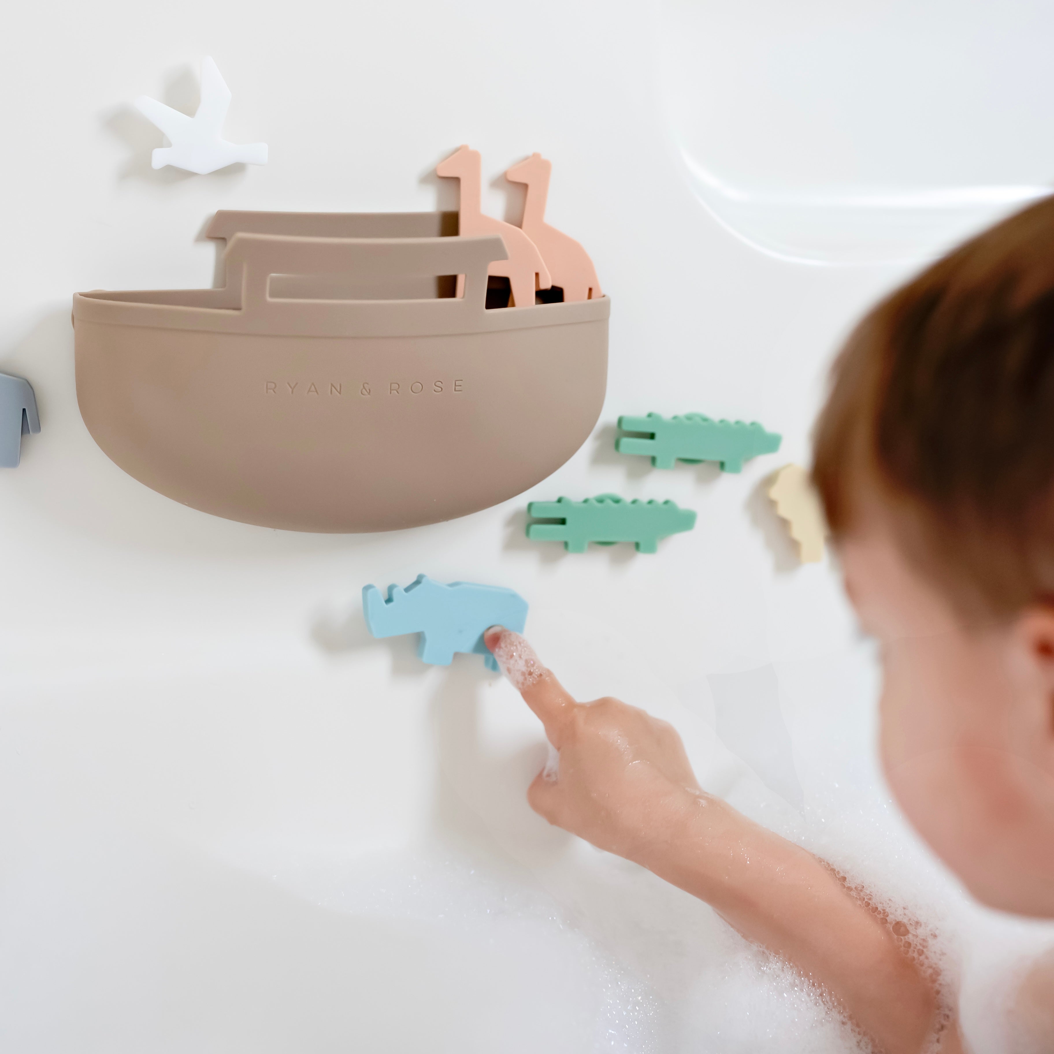 Toddler in bath tub playing with Noah’s Ark toy