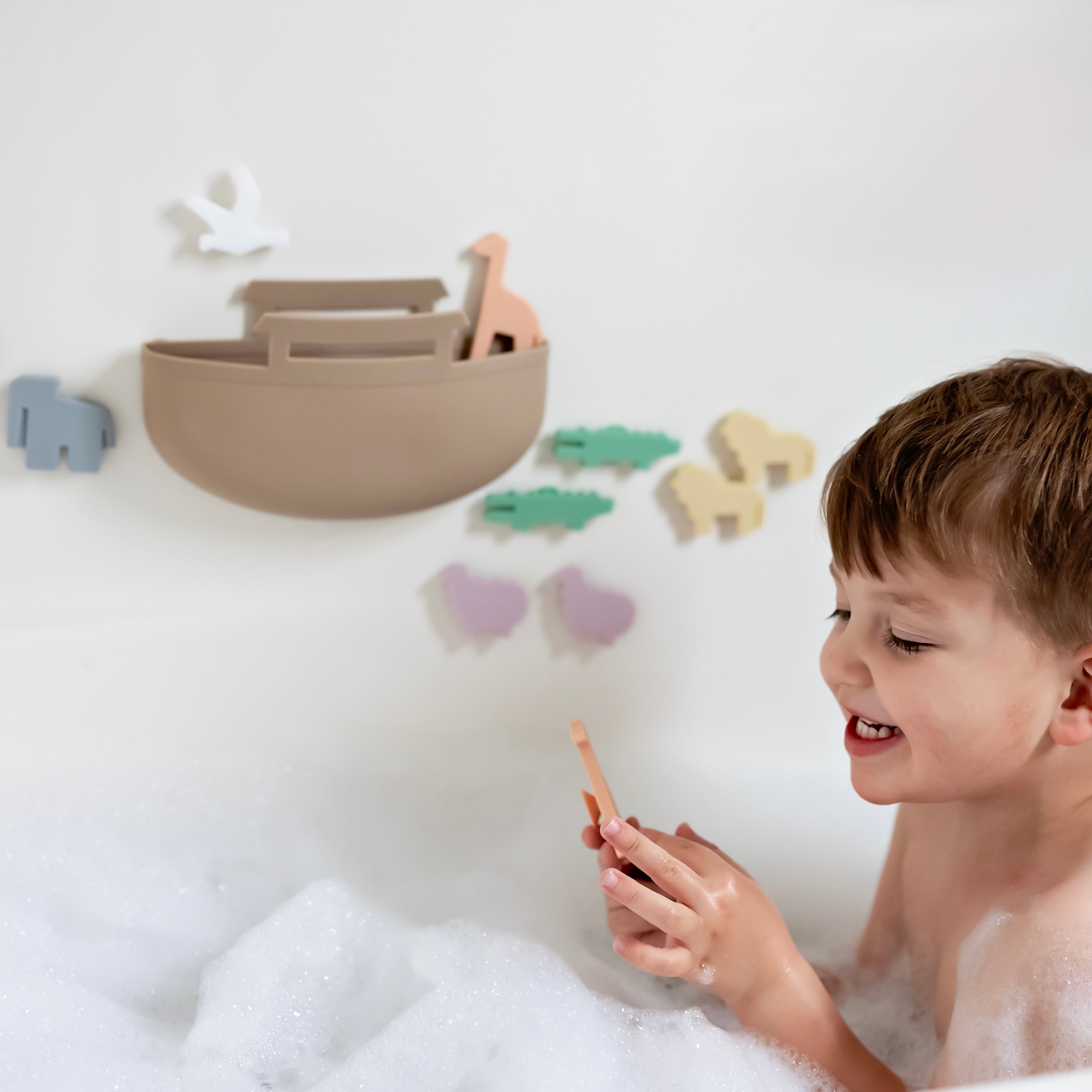 Toddler in bath tub playing with Noah’s Ark toy