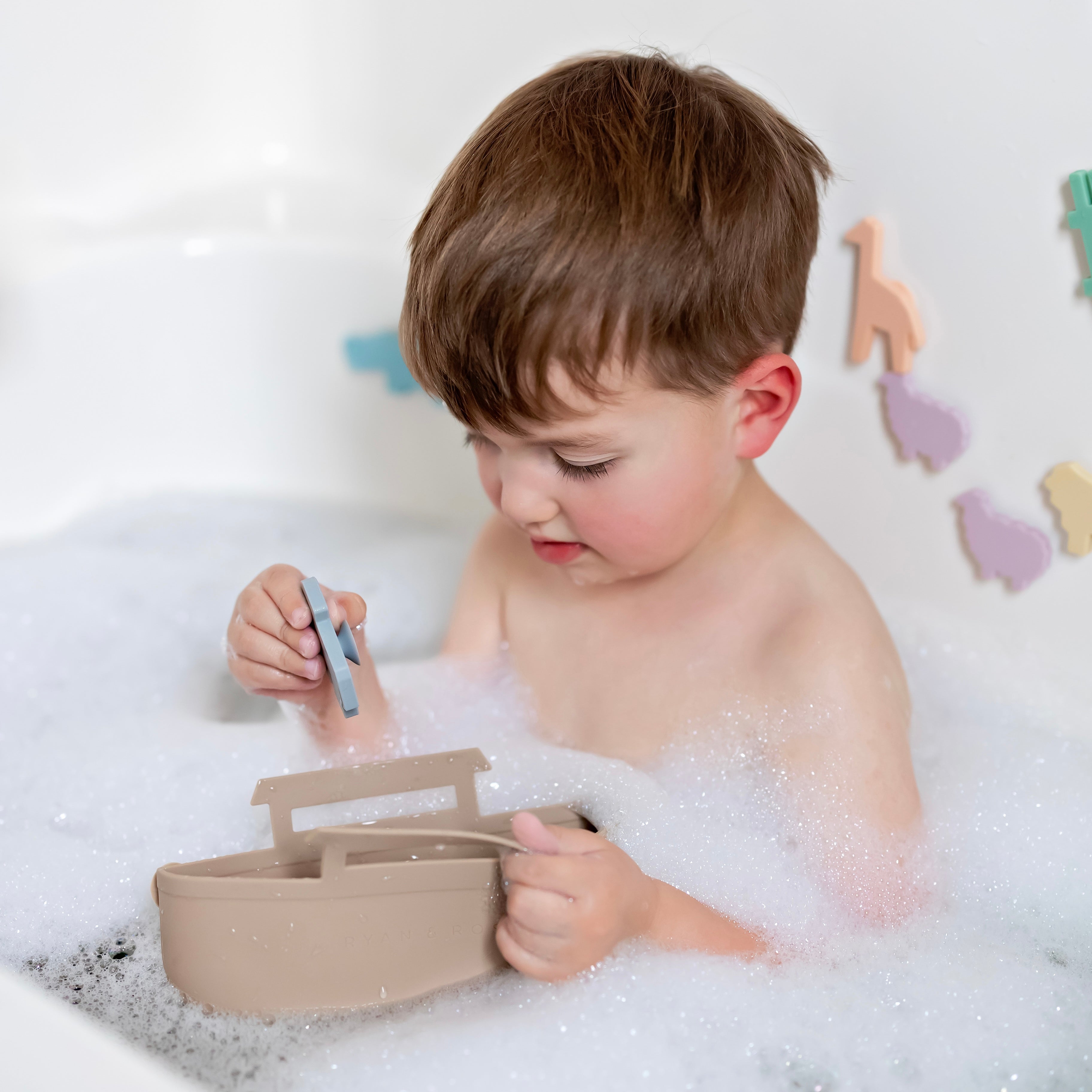 Toddler in bath tub playing with Noah’s Ark toy