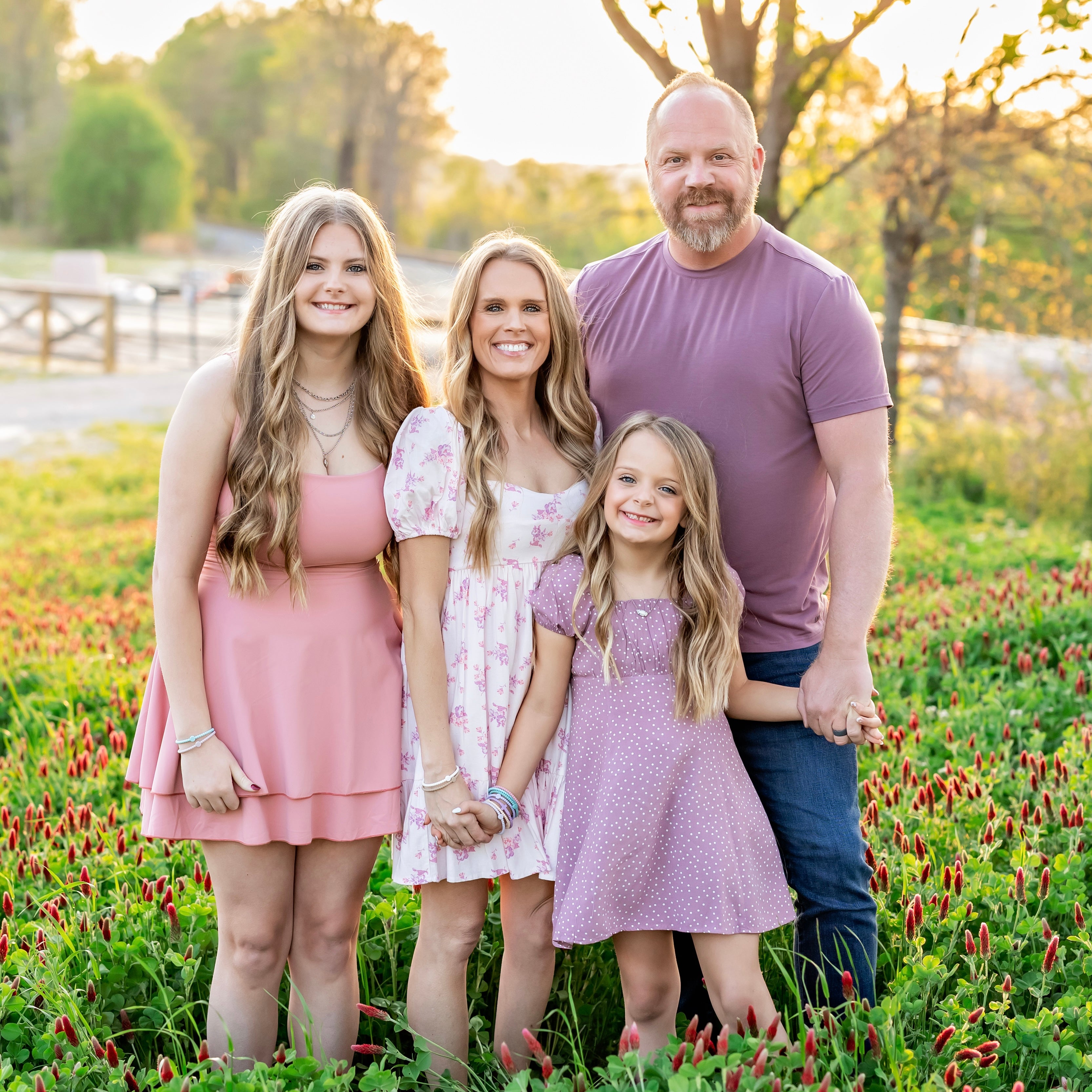 Family of four standing in a field with wildflowers during sunset.