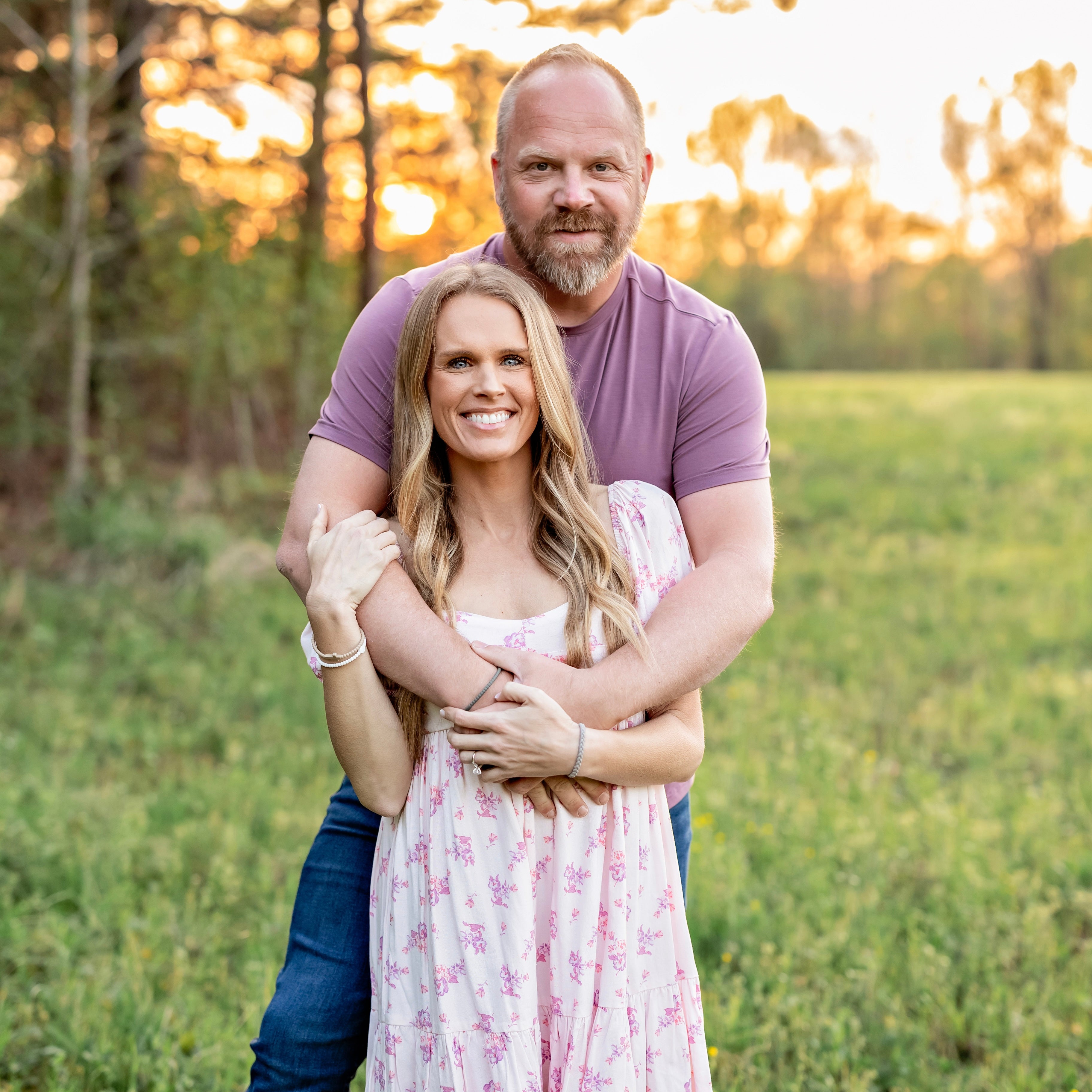 Couple embracing in a field with a sunset background