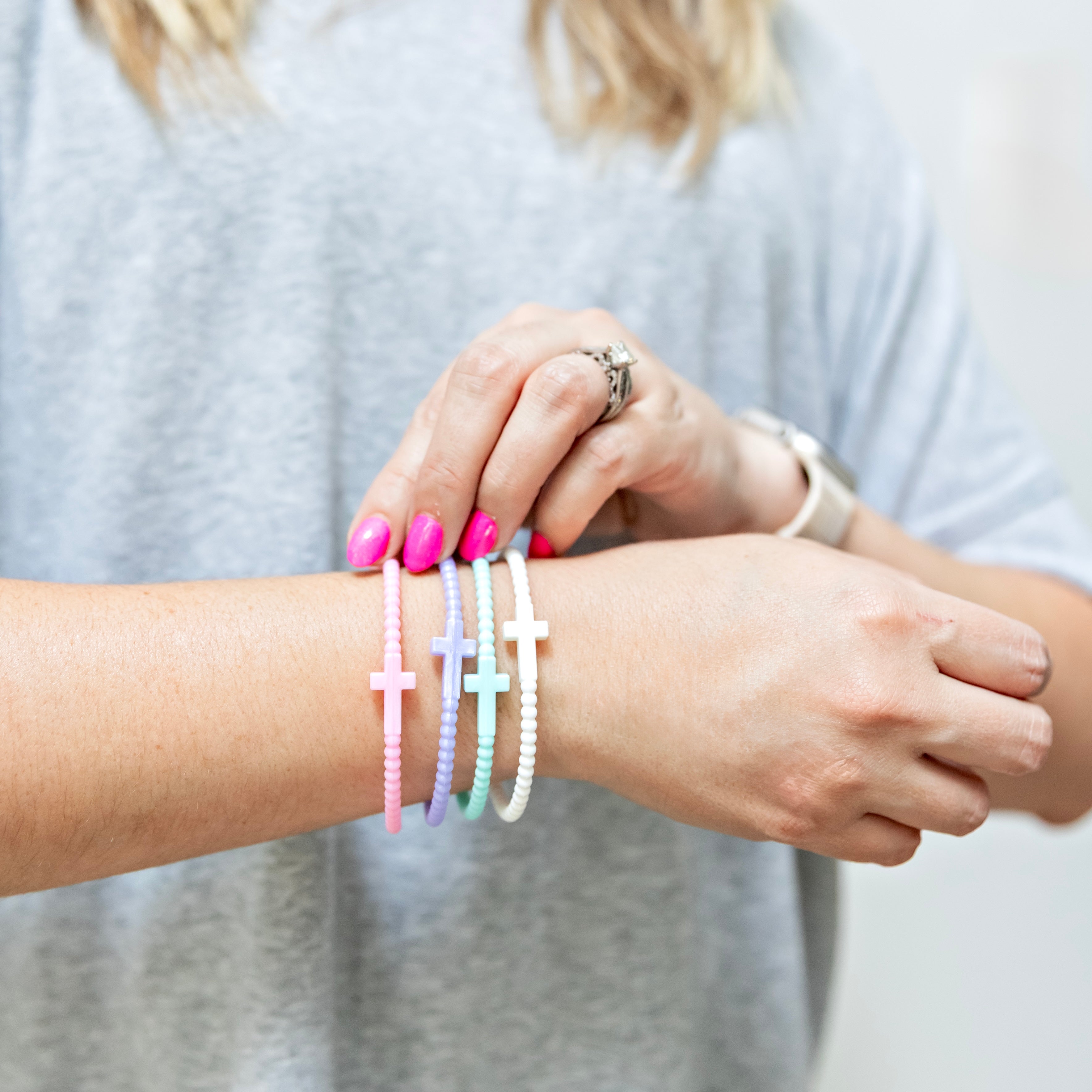 Close-up of a person wearing colorful bracelets on a plain background