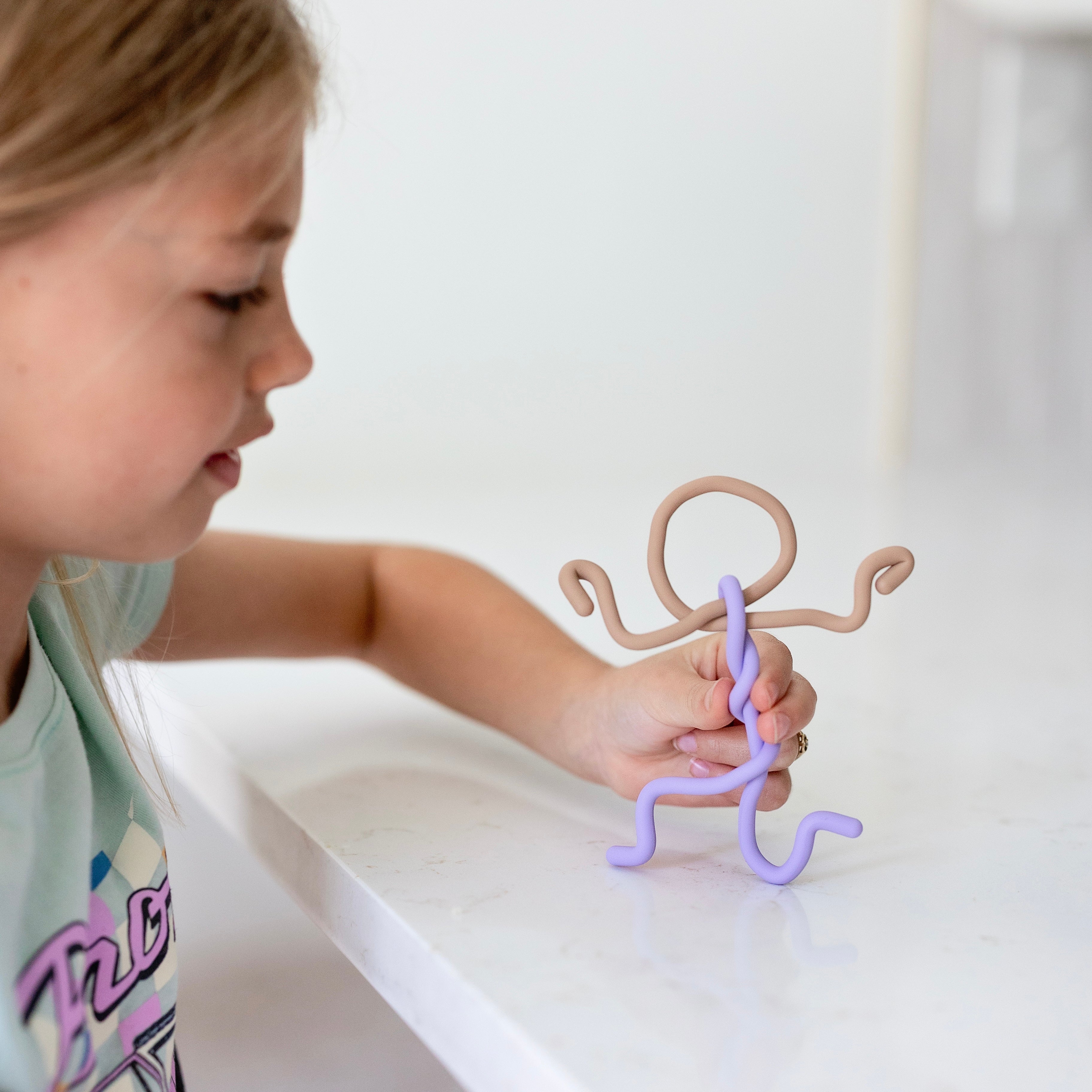 Child playing with a toy figure on a white surface