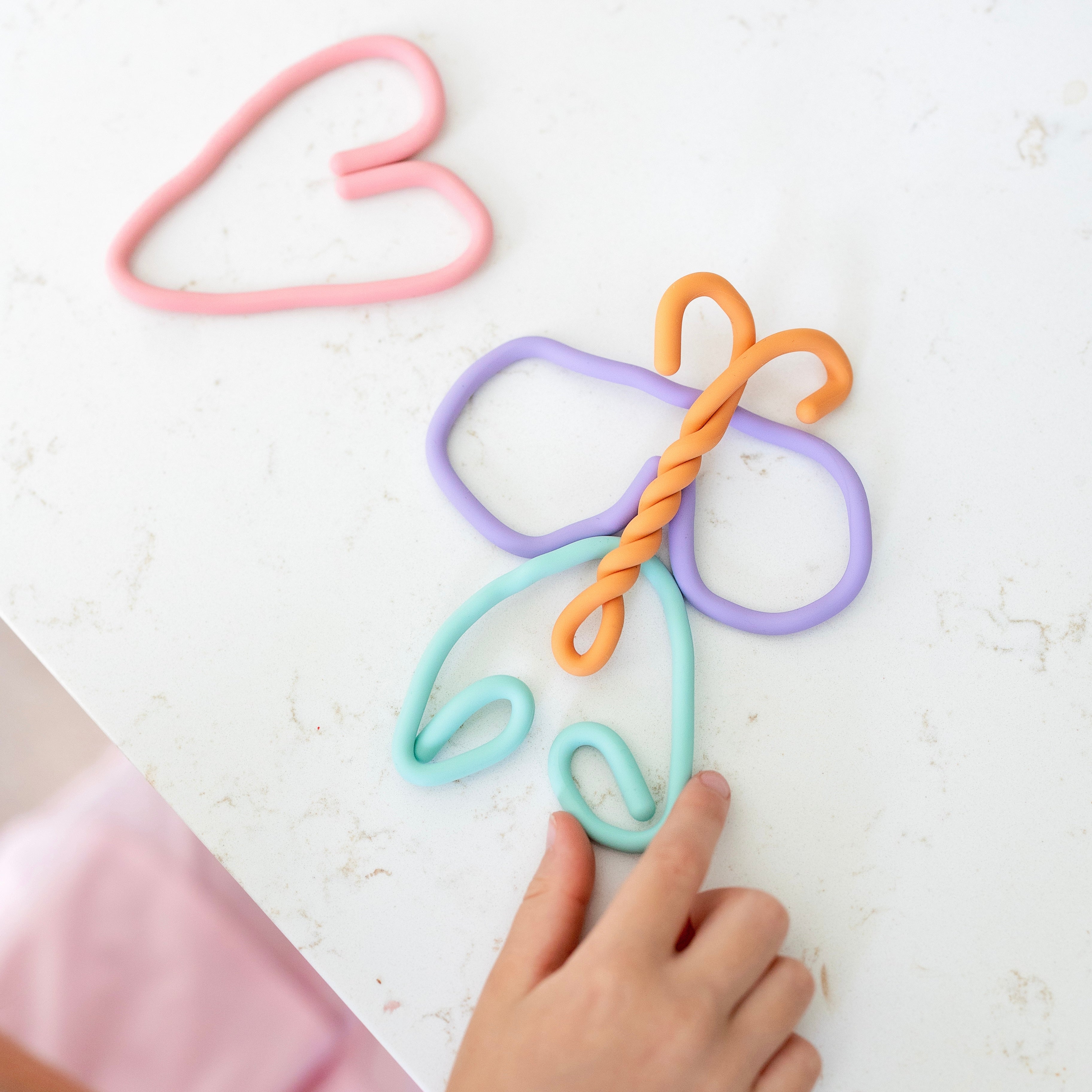 Colorful butterfly-shaped hair clips on a white surface with a hand reaching out.