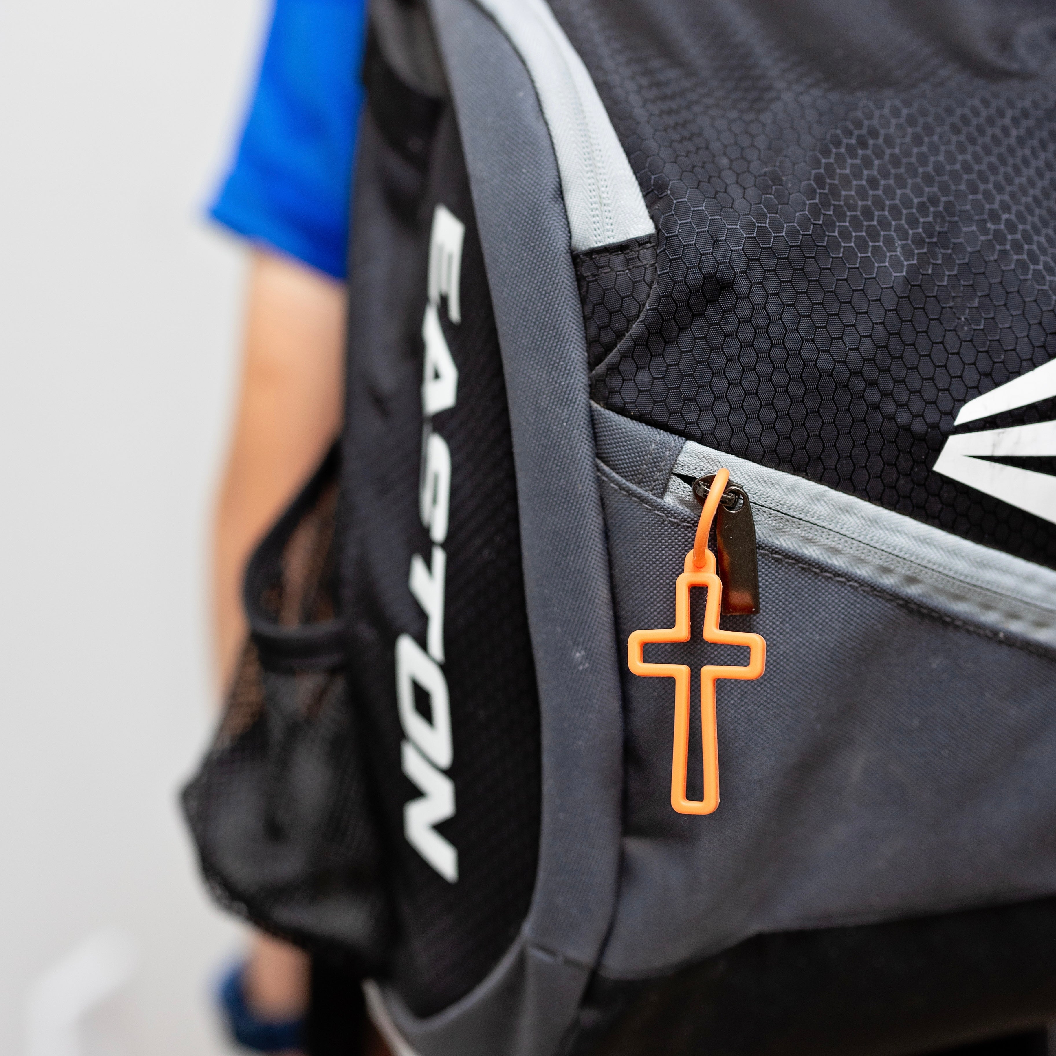 Gray backpack with a cross charm on a blurred background