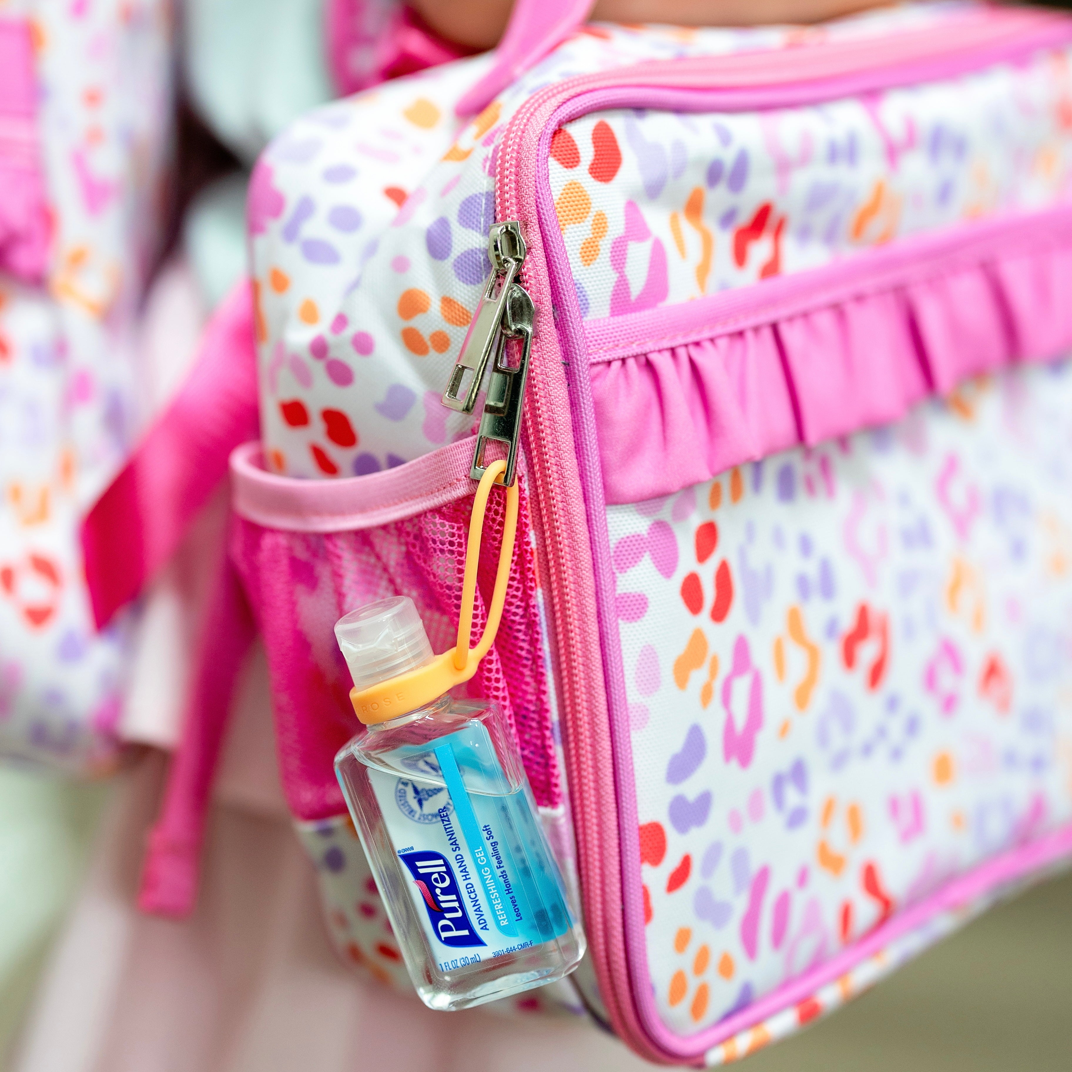Colorful backpack with a small bottle of Purell attached to the zipper.