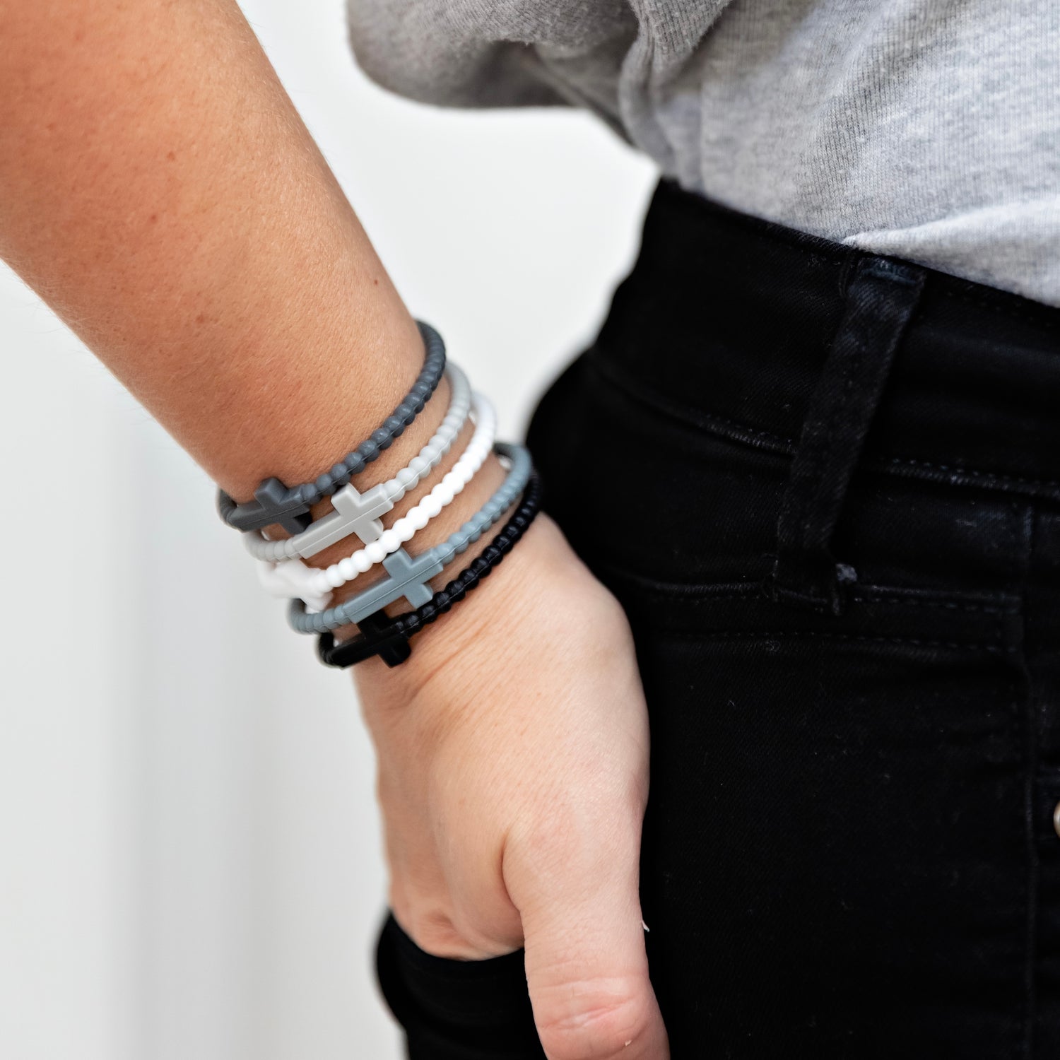 Person wearing multiple bracelets on a plain background