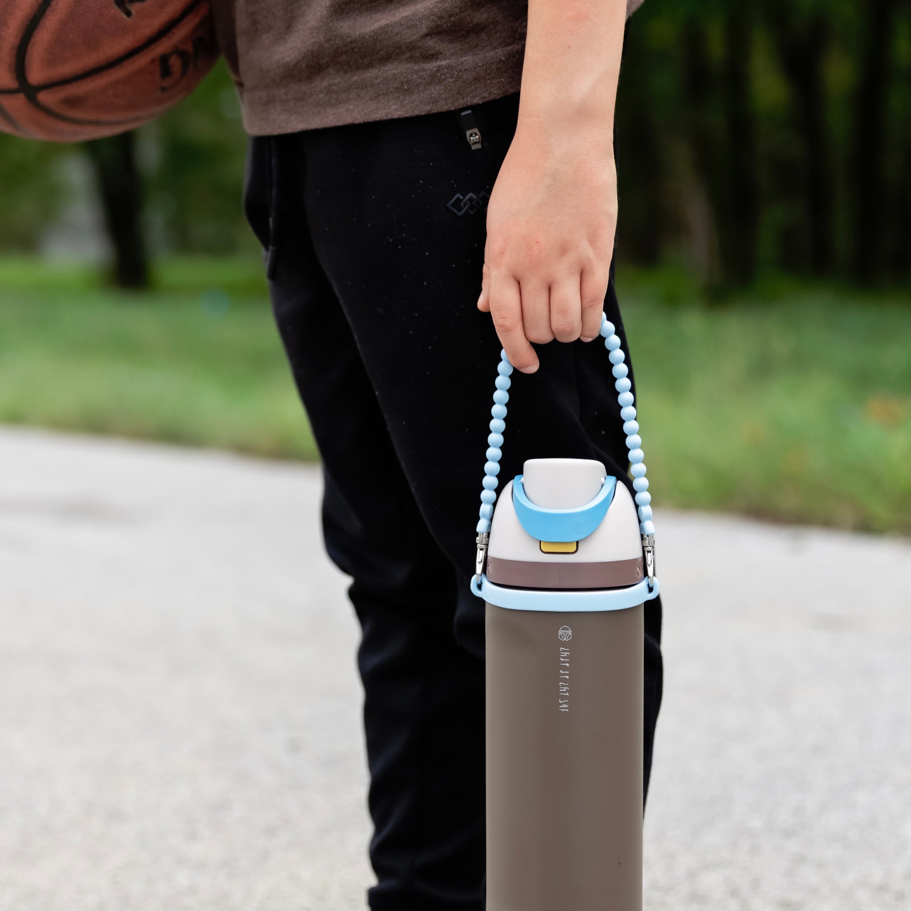 Person holding a basketball with a blue handle outdoors