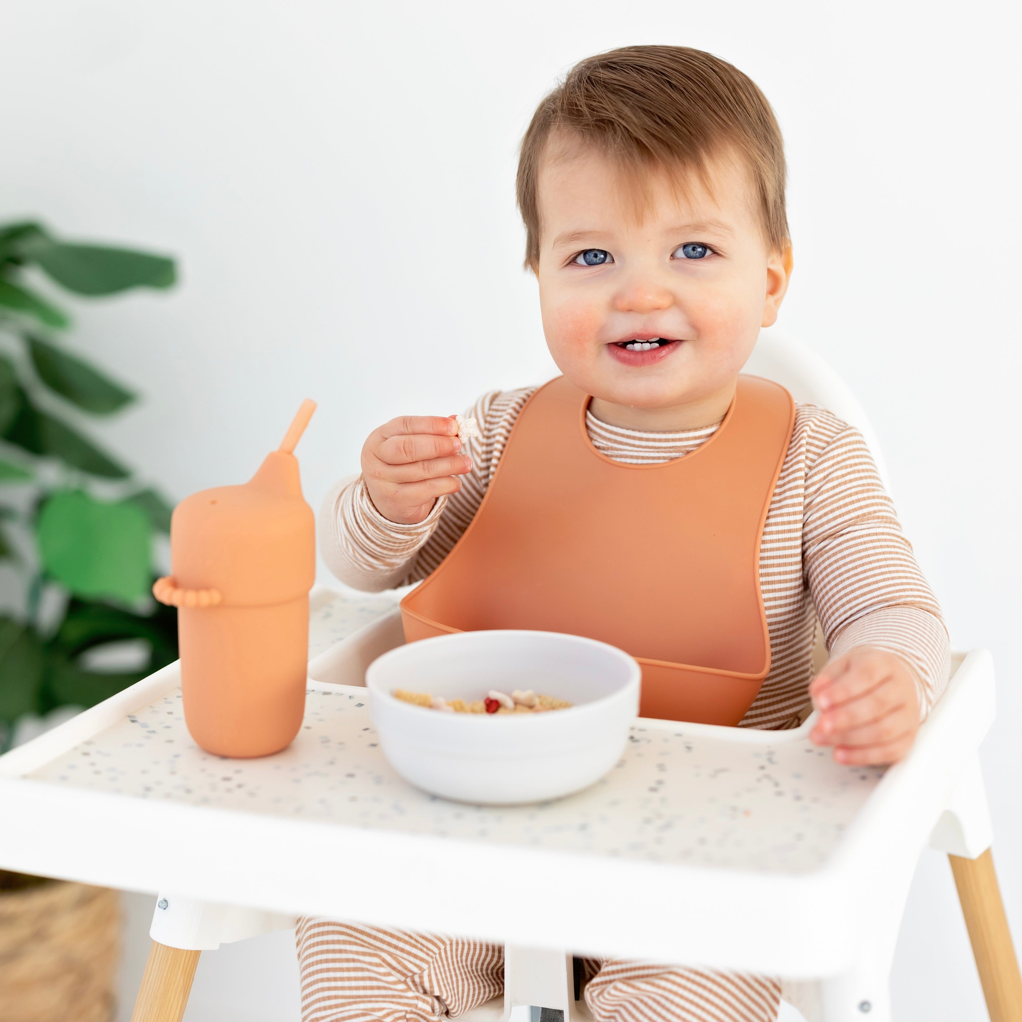 Baby in a high chair eating with Ryan &amp; Rose accessories