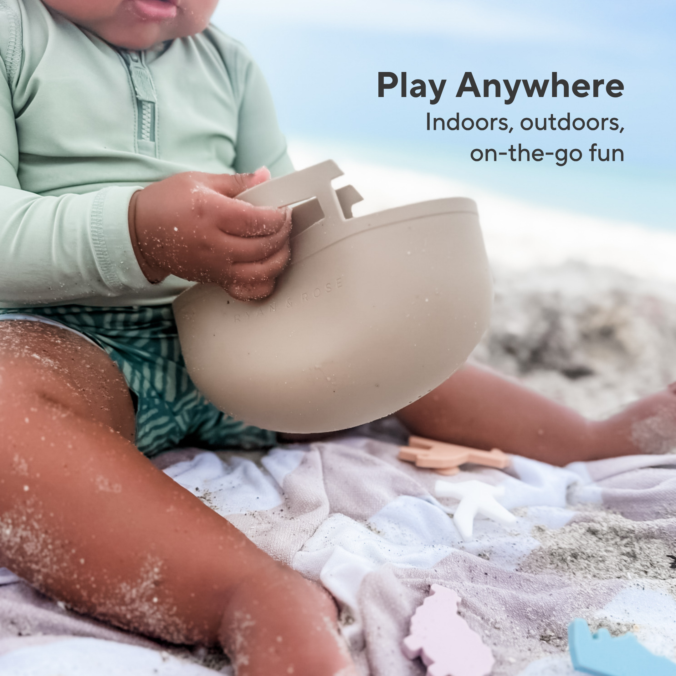 Child playing with a sand toy on a beach, with text &