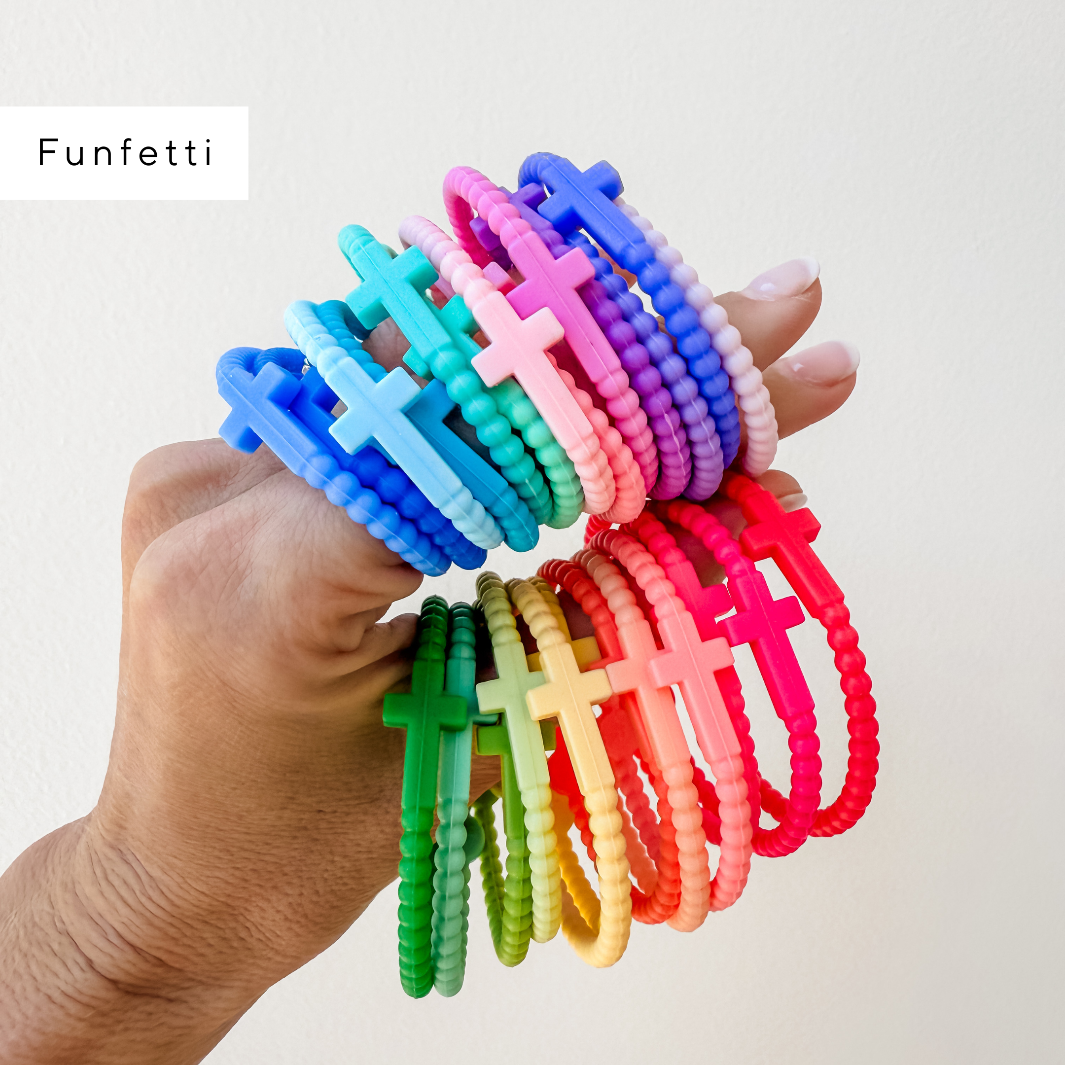 Colorful cross-shaped bracelets held by a hand on a white background with &