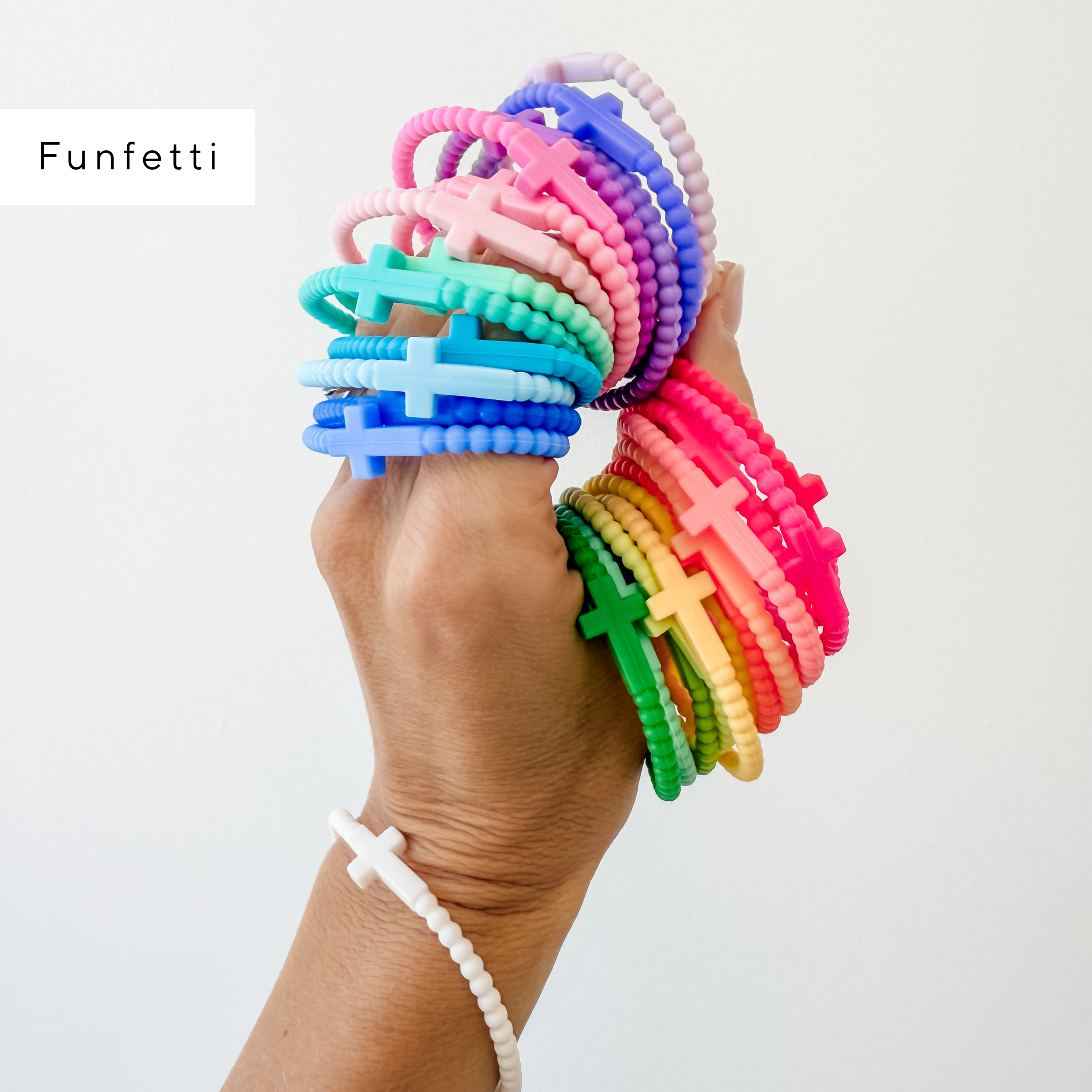 Hand holding colorful bracelets with a rainbow pattern against a white background