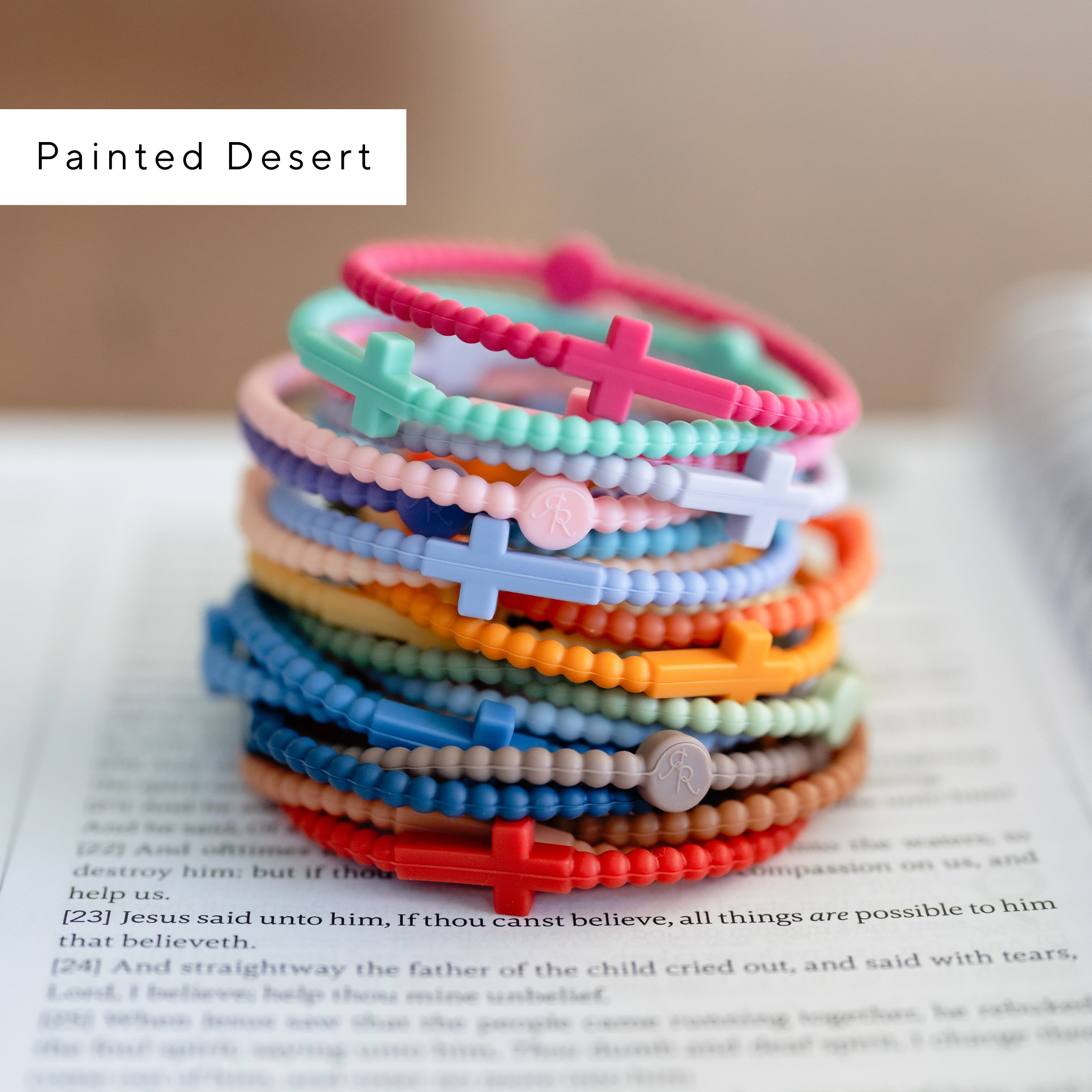 Stack of colorful beaded bracelets with cross charms on a book page, labeled &