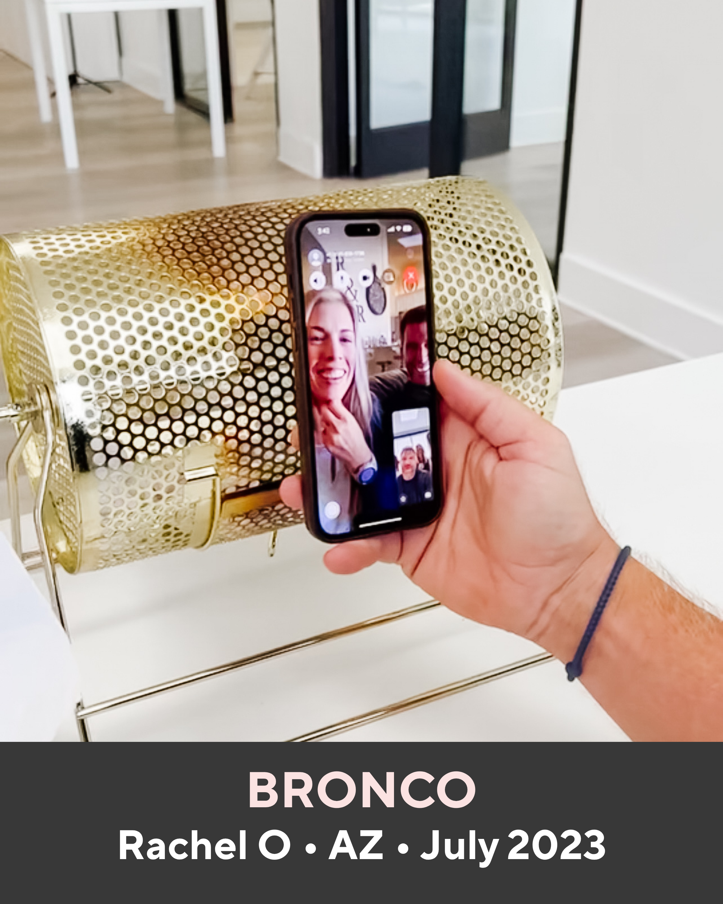 Hand holding a phone with a video call on a gold clutch in a room.