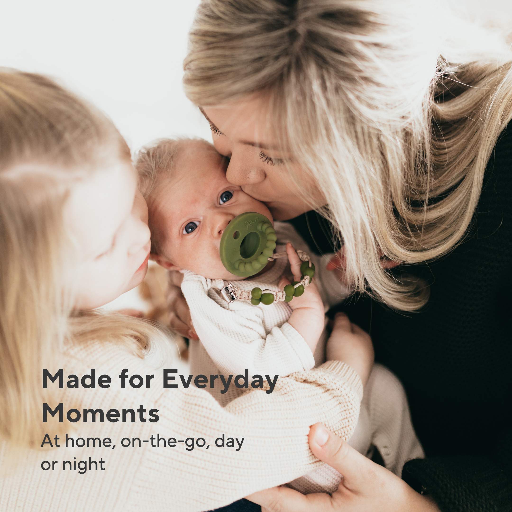 Woman holding a baby with a pacifier, surrounded by two older children, with text &