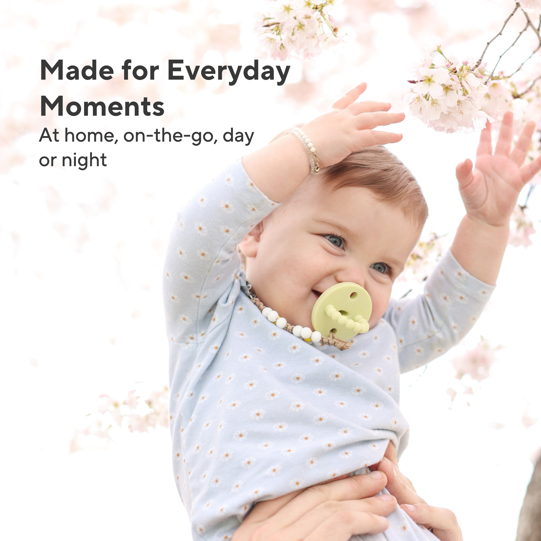 Baby wearing a light blue outfit with a pacifier, surrounded by cherry blossoms with text &