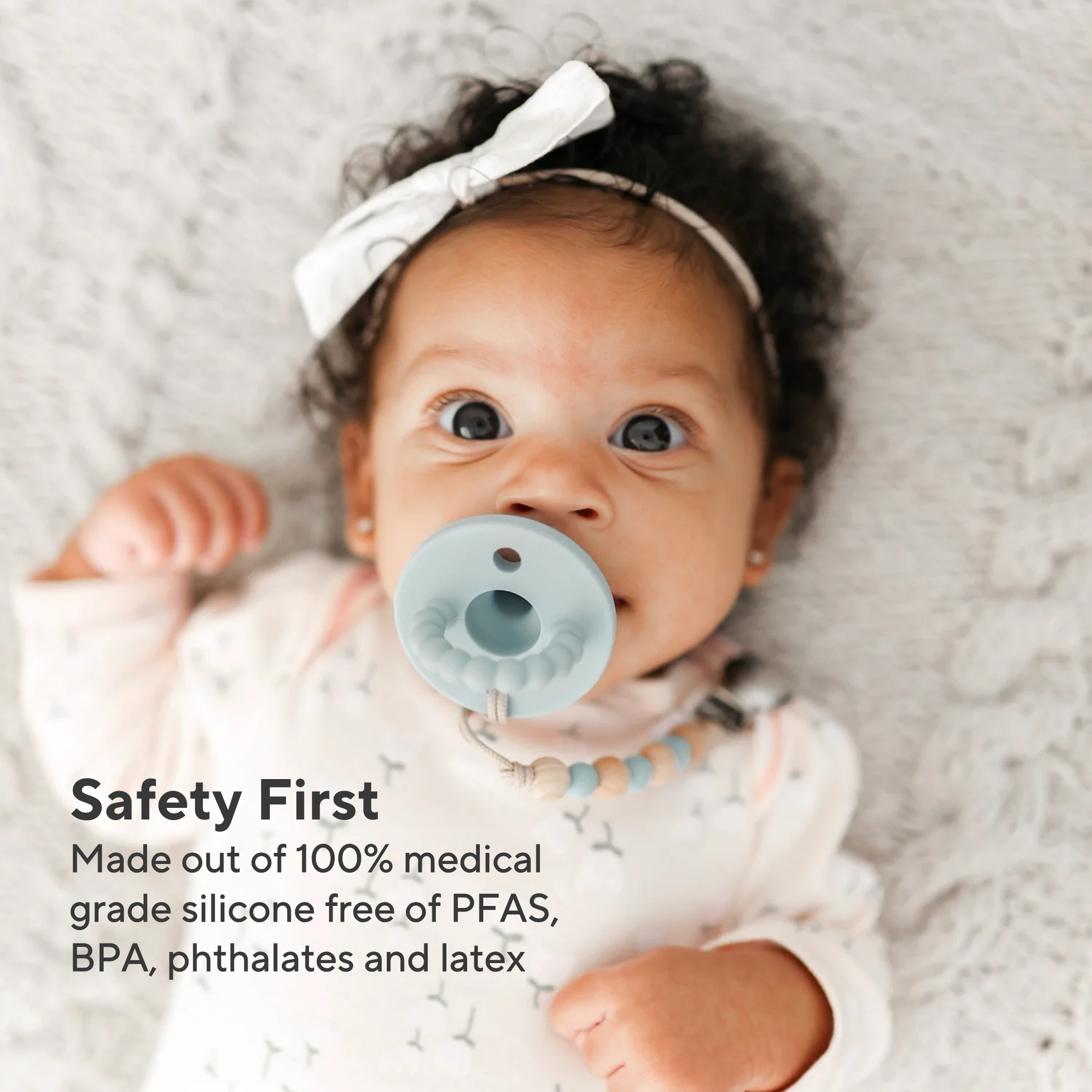 Baby wearing a pacifier with text about safety and material quality.