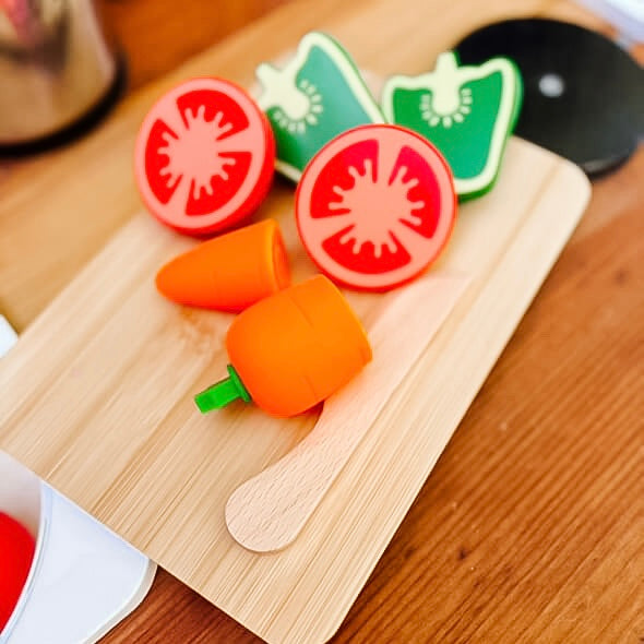 Toy vegetables on a wooden cutting board with a kitchen background