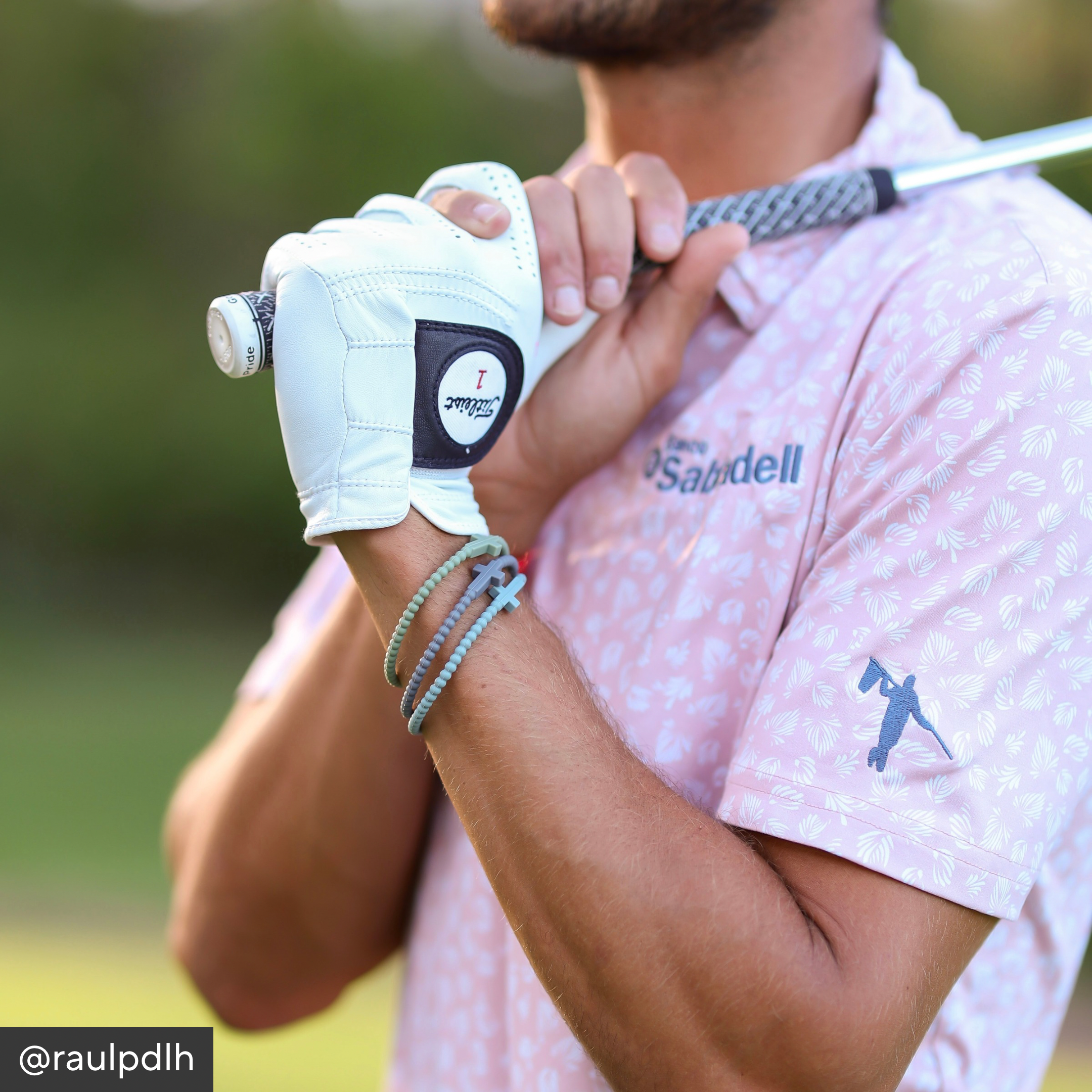 Person holding a golf club with a glove on a blurred green background