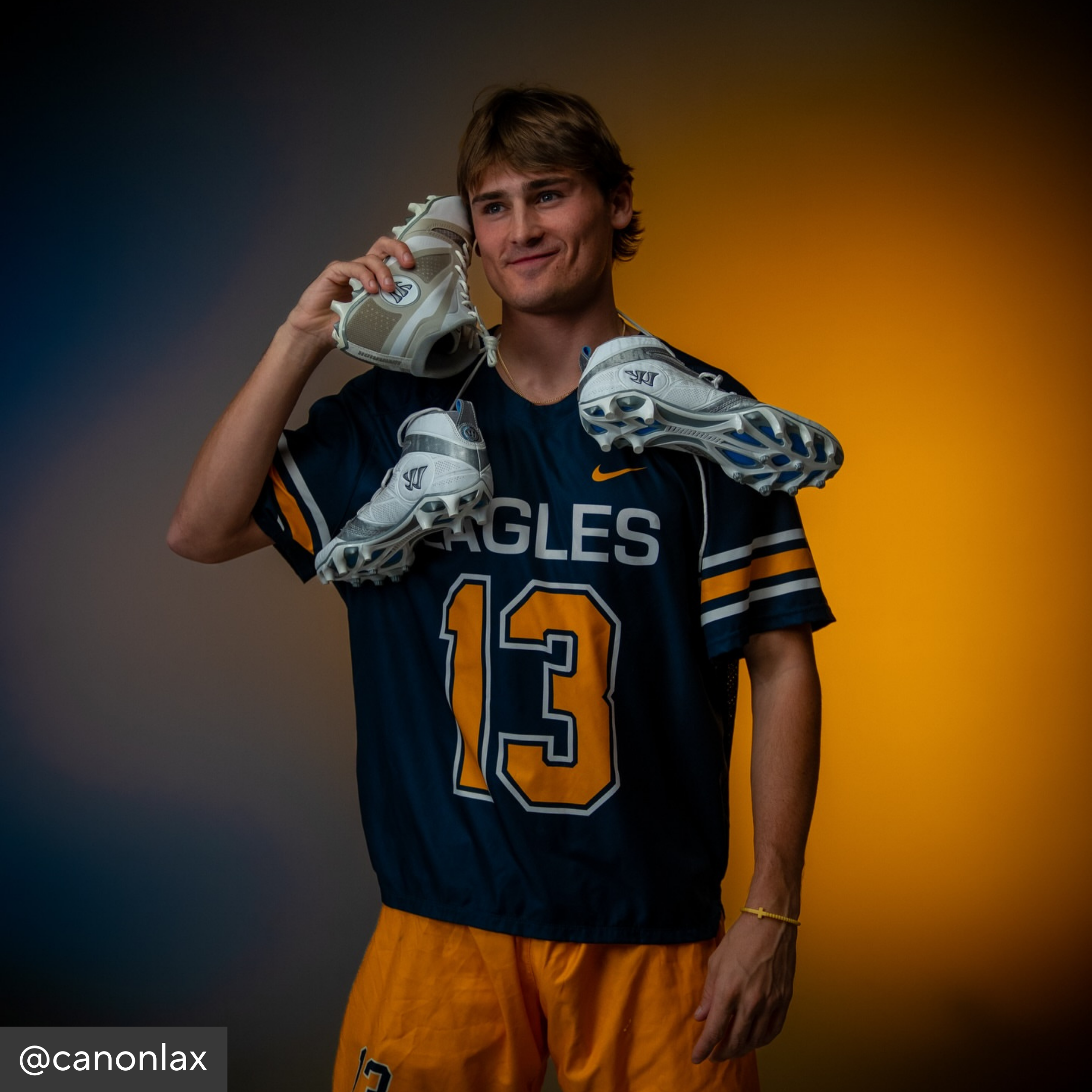 Person wearing a sports jersey with number 13 and holding sports shoes against a gradient background