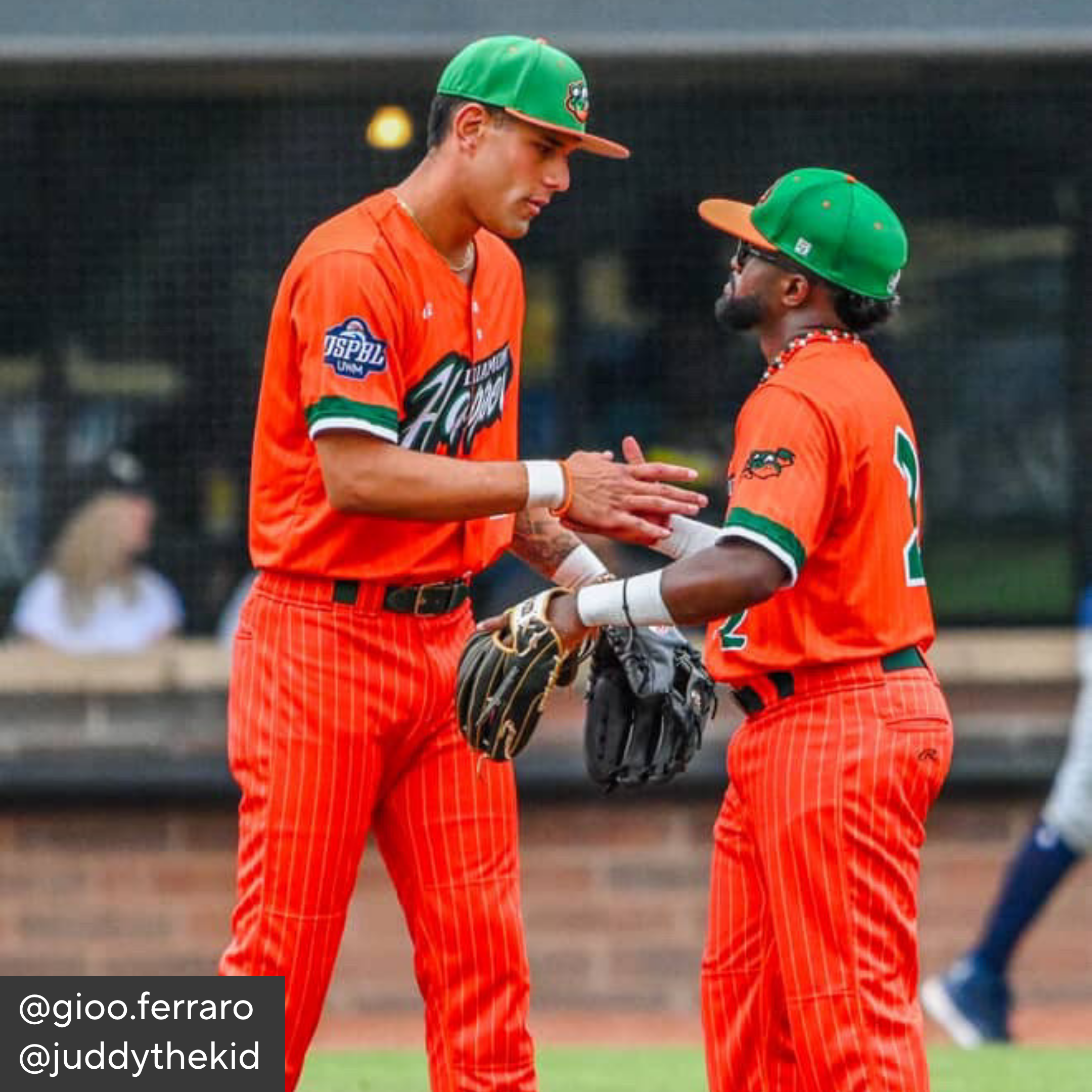Two baseball players in orange uniforms shaking hands on a baseball field.