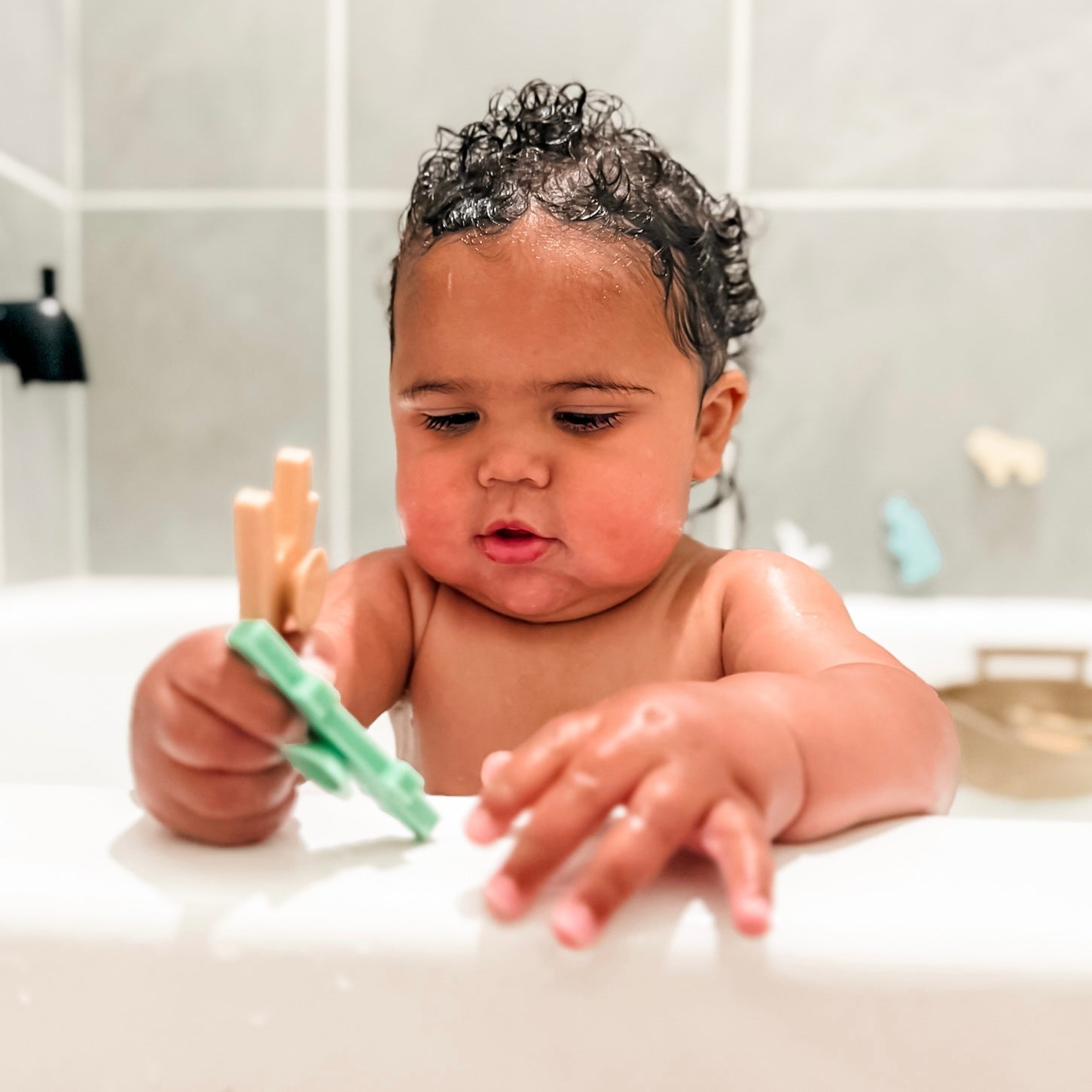 Baby in bath playing with Noah’s Ark toy