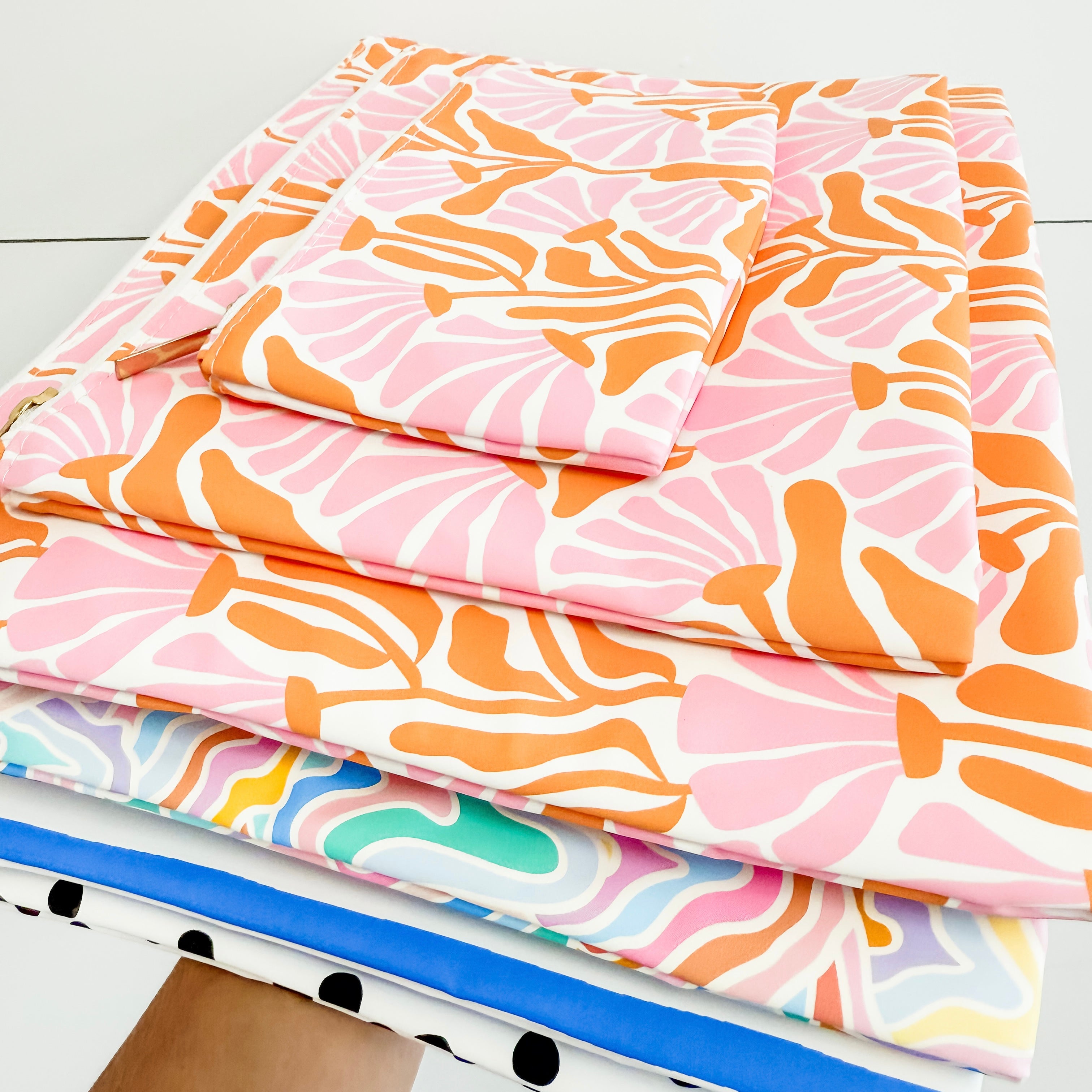Stack of colorful fabric sheets with abstract patterns on a white surface
