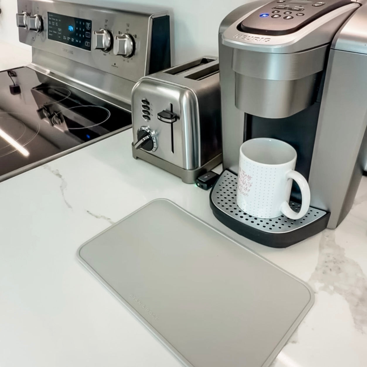 Kitchen counter with coffee maker, toaster, and mug on a white marble surface