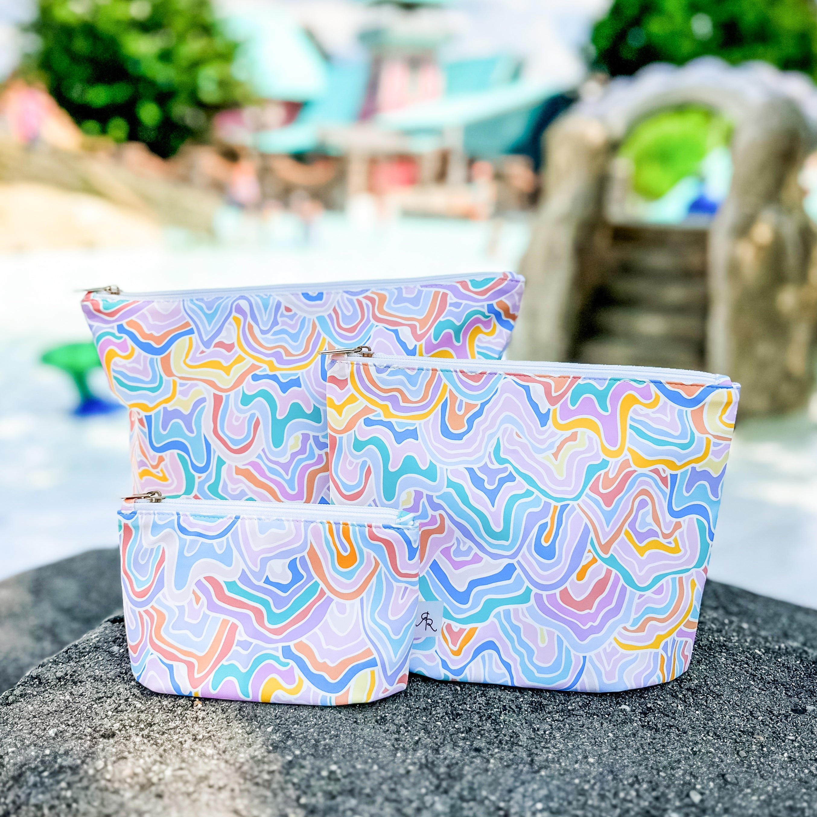 Three colorful patterned bags on a beach with blurred background