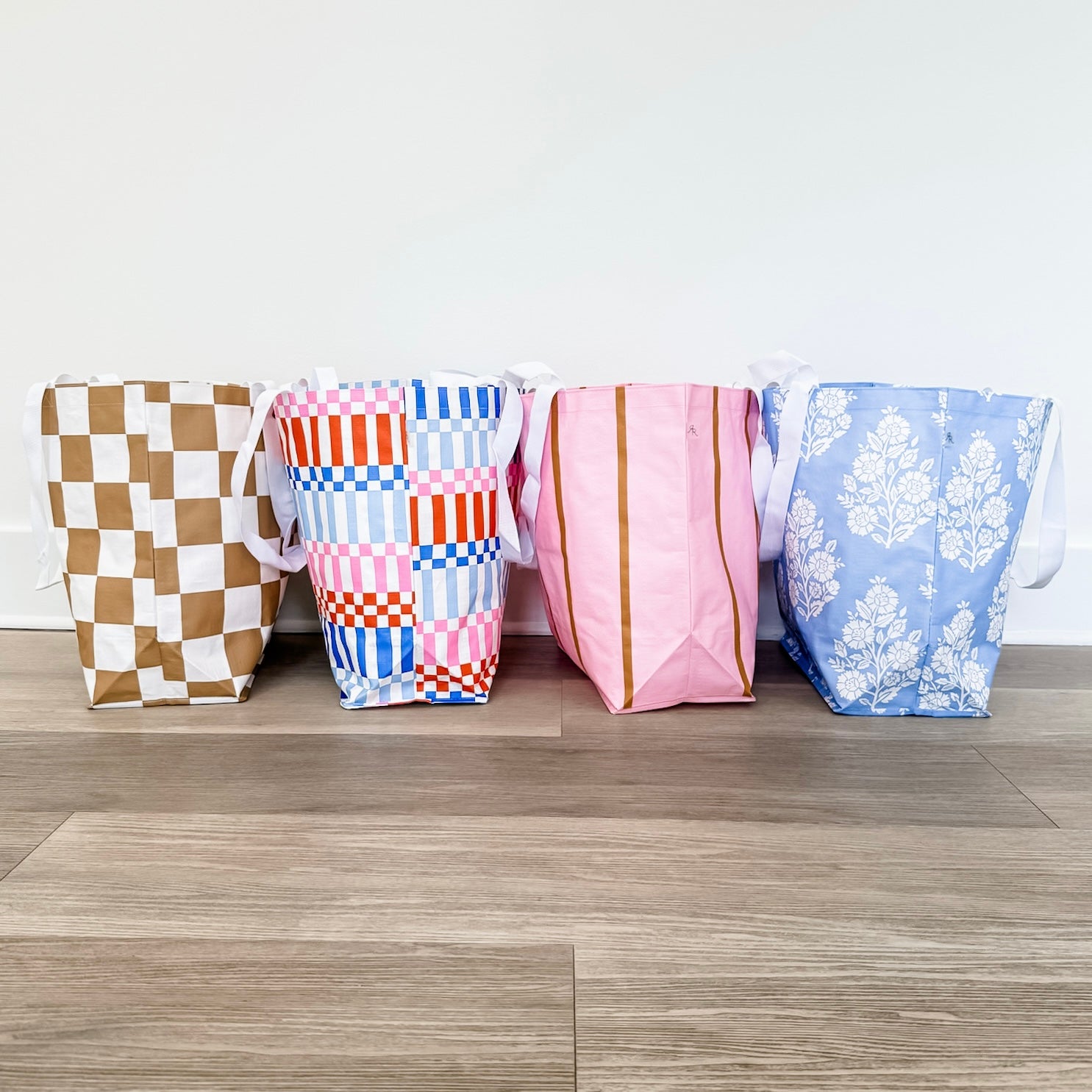Four colorful fabric bags with different patterns on a wooden floor.