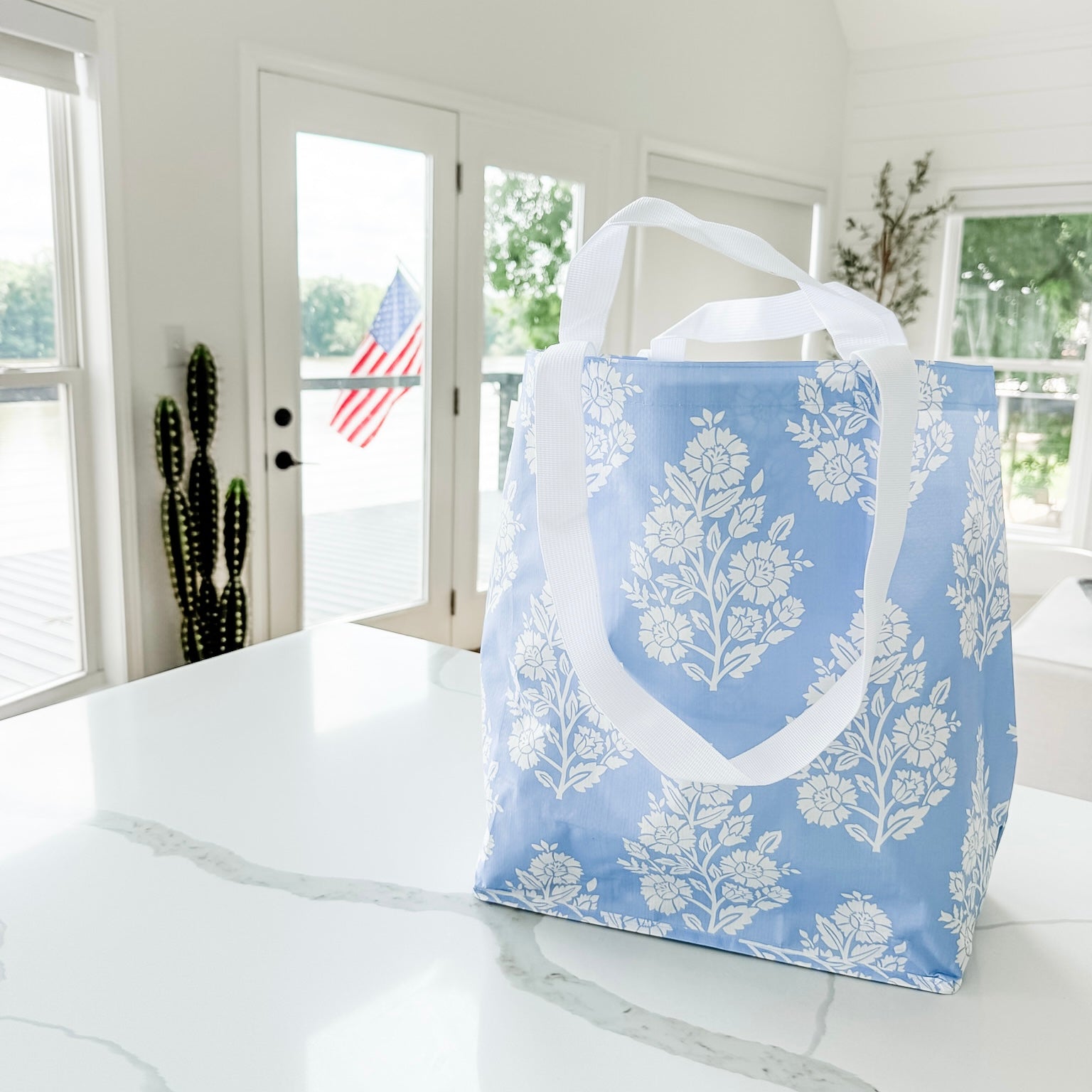 Blue tote bag with white floral pattern on a marble surface