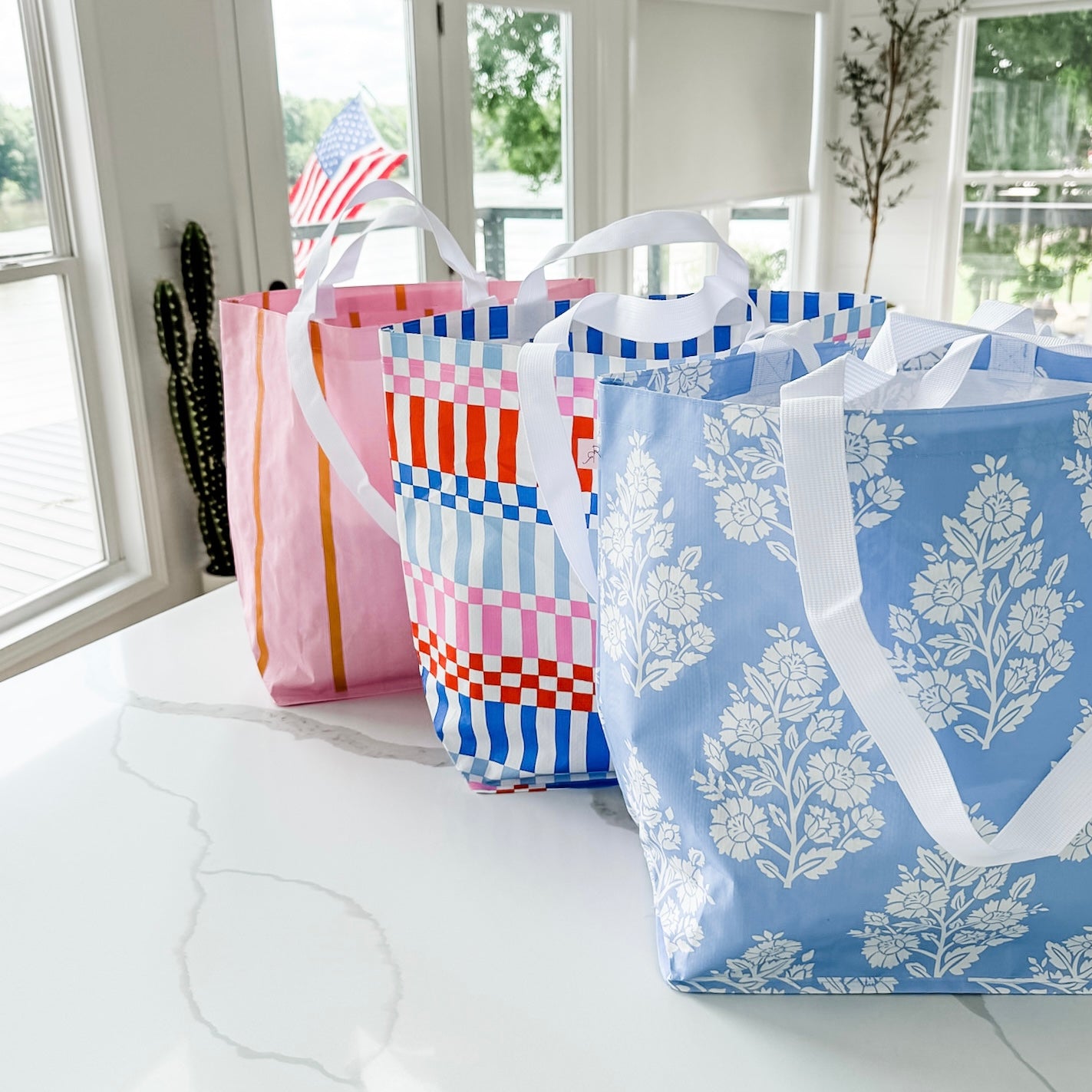 Four patterned tote bags on a white surface with a window in the background