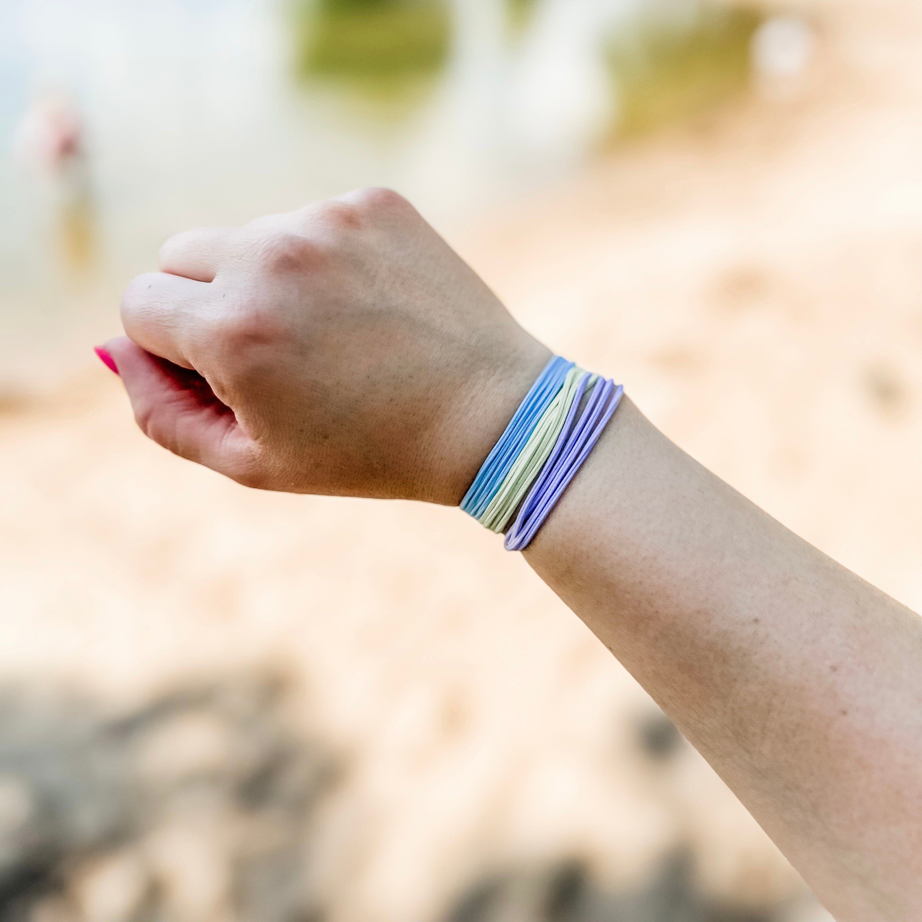 Hand wearing a colorful bracelet with a blurred natural background