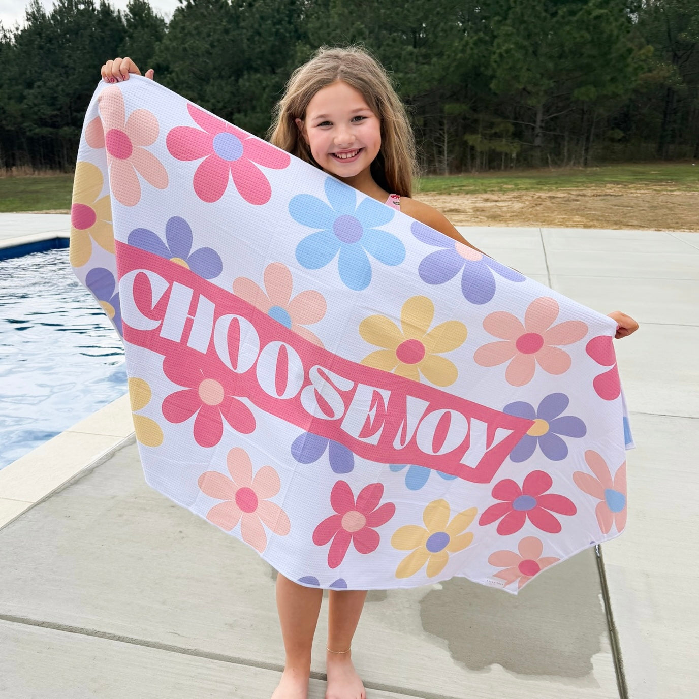 Child holding a colorful towel with &