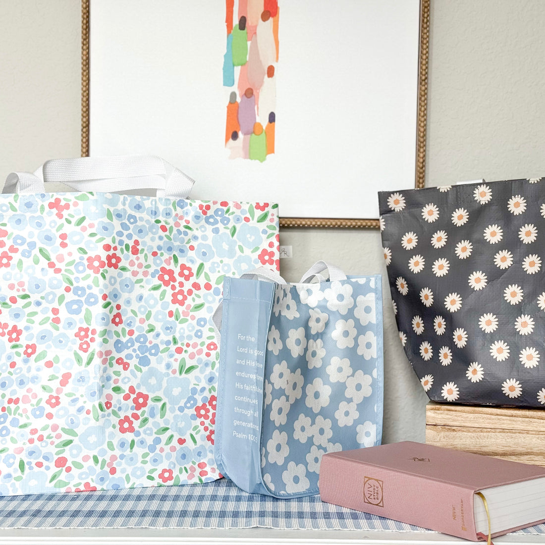 Three floral-patterned bags on a surface with a book in the foreground.