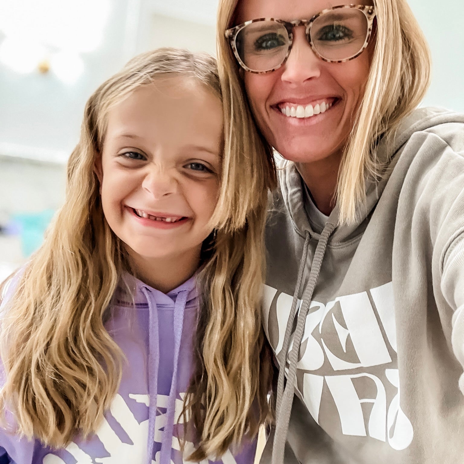 Two people, a woman and a young girl, wearing hoodies with visible branding.