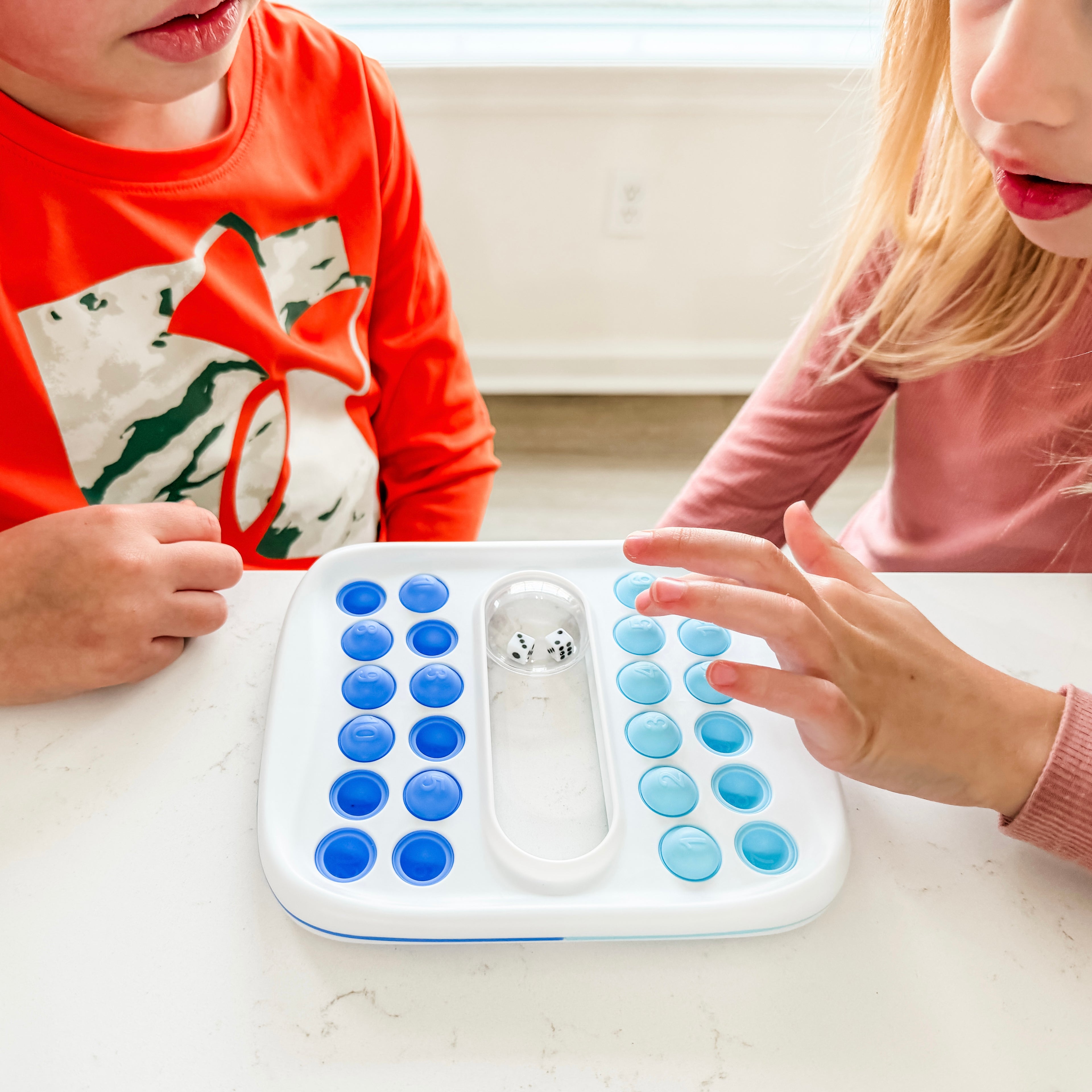 Two children playing with a toy game on a table.