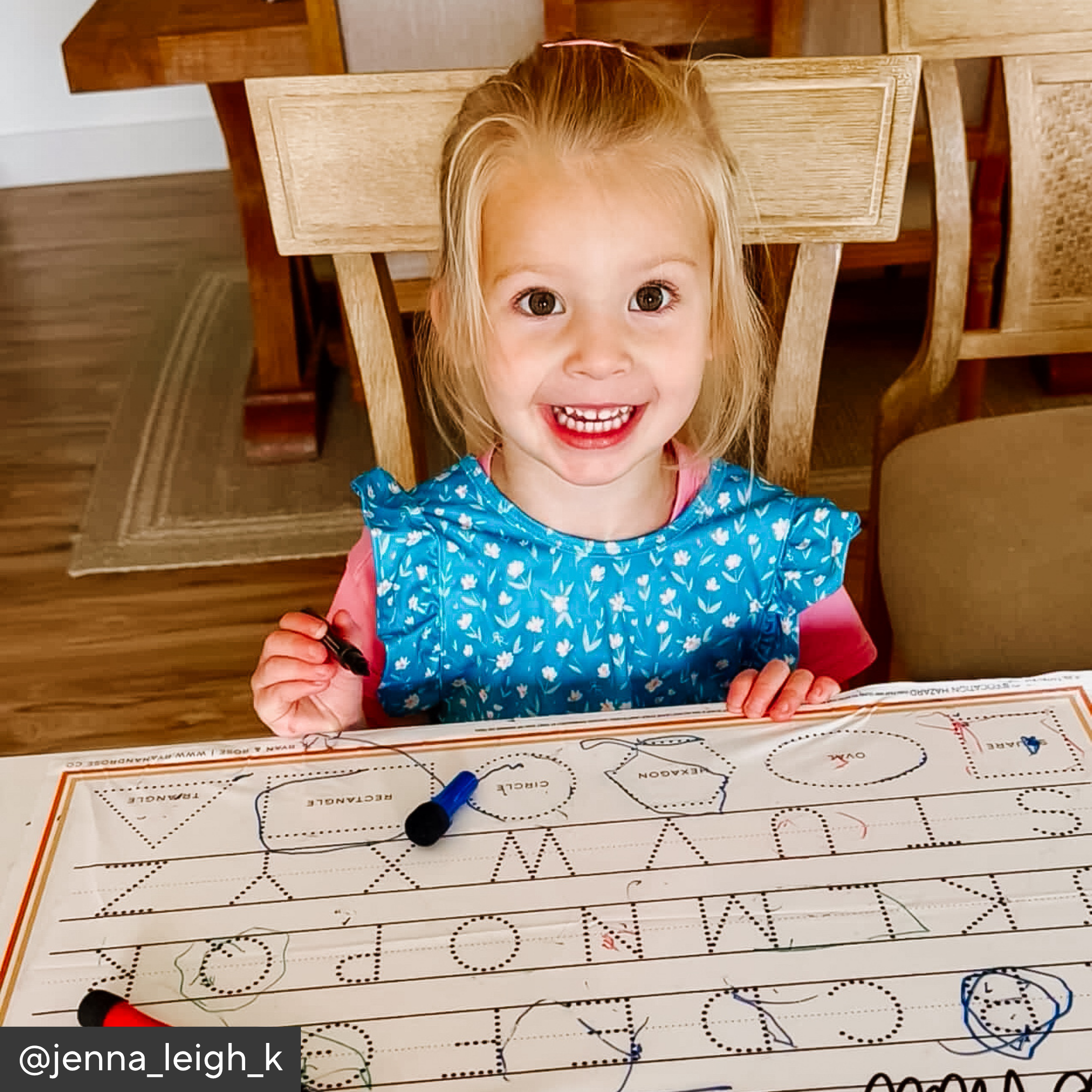 Child sitting at a table with a coloring book and crayons, wearing a blue bib.