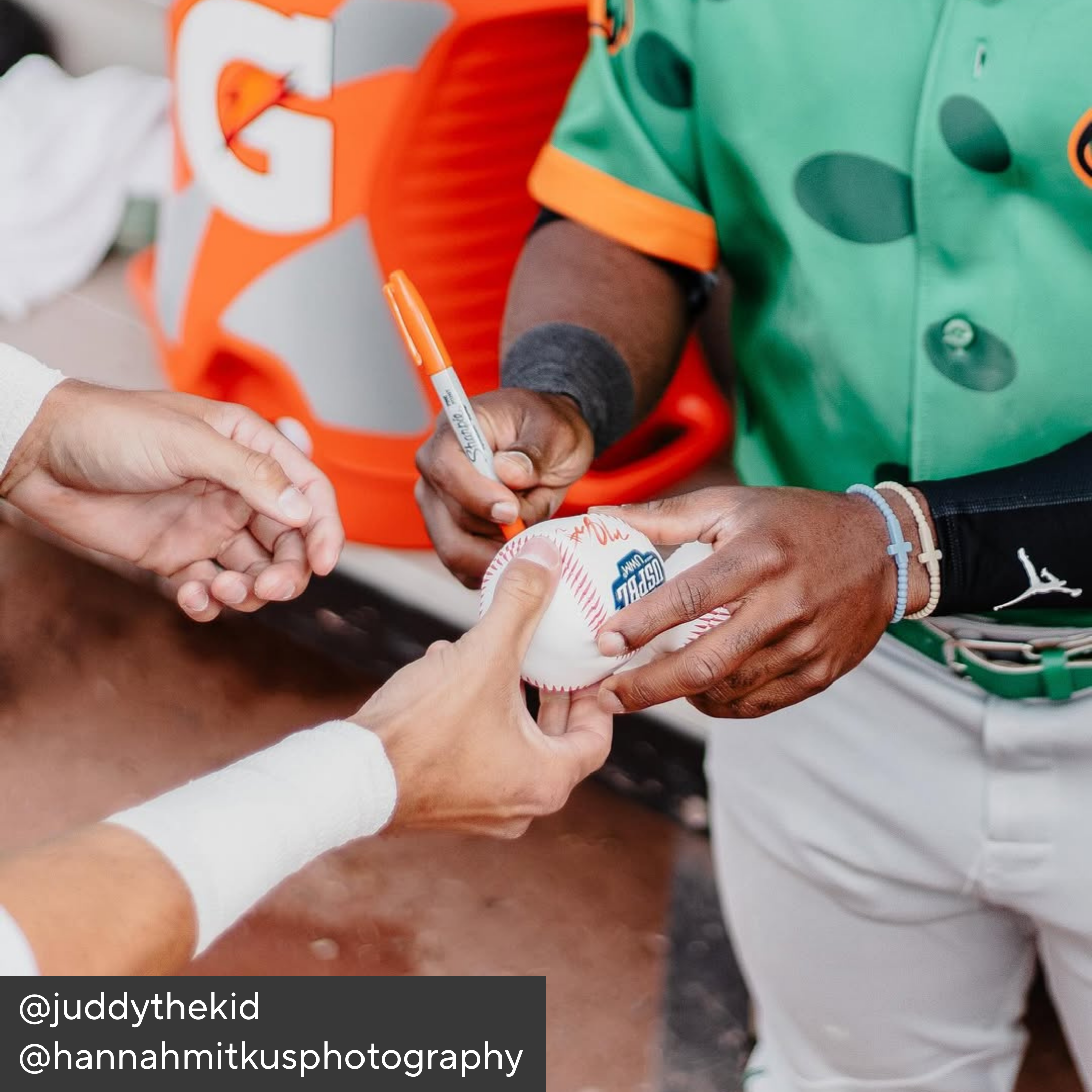 Person in sports uniform holding a baseball with another person, with a focus on the interaction.