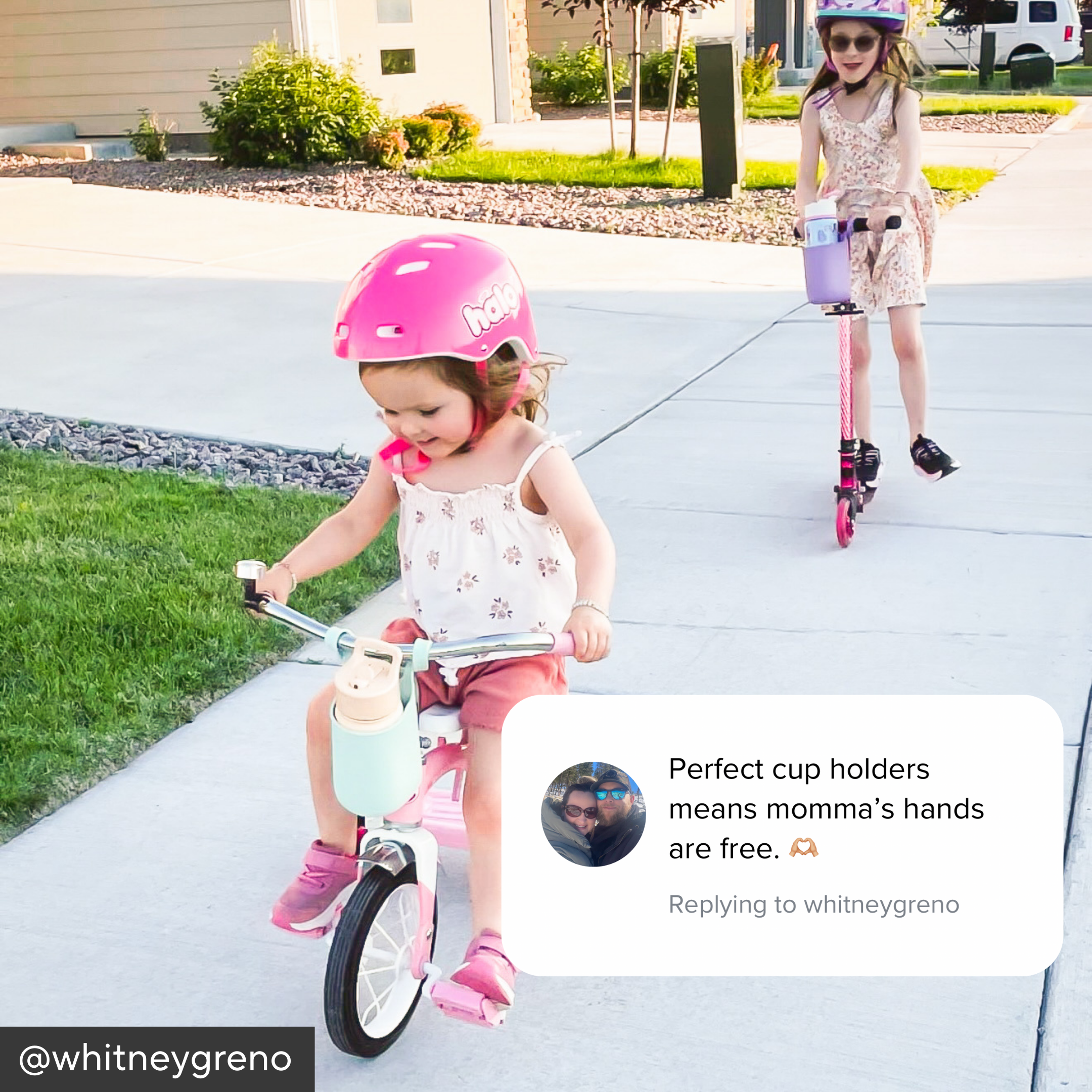 Two children riding bikes with pink helmets on a sidewalk.