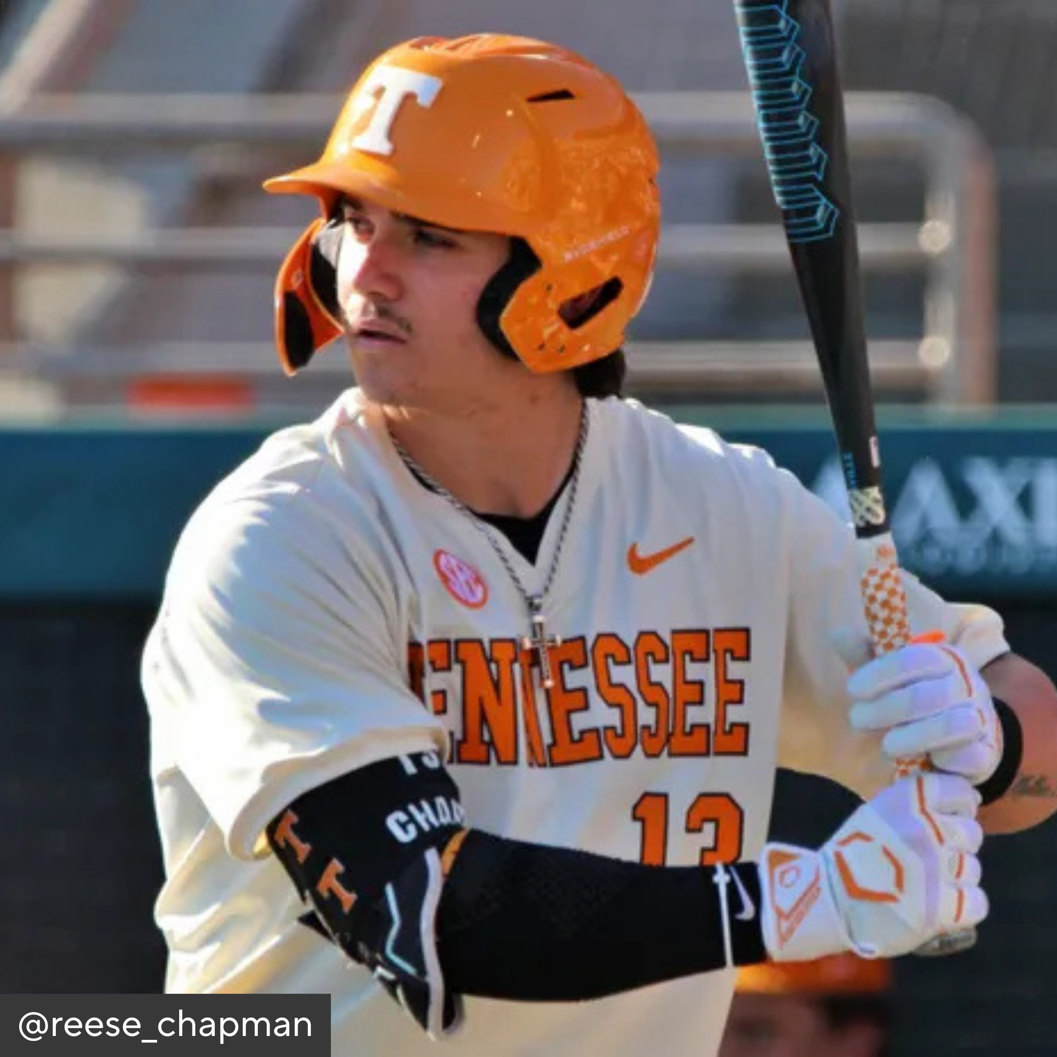 Baseball player in Tennessee uniform with orange helmet and bat, blurred background