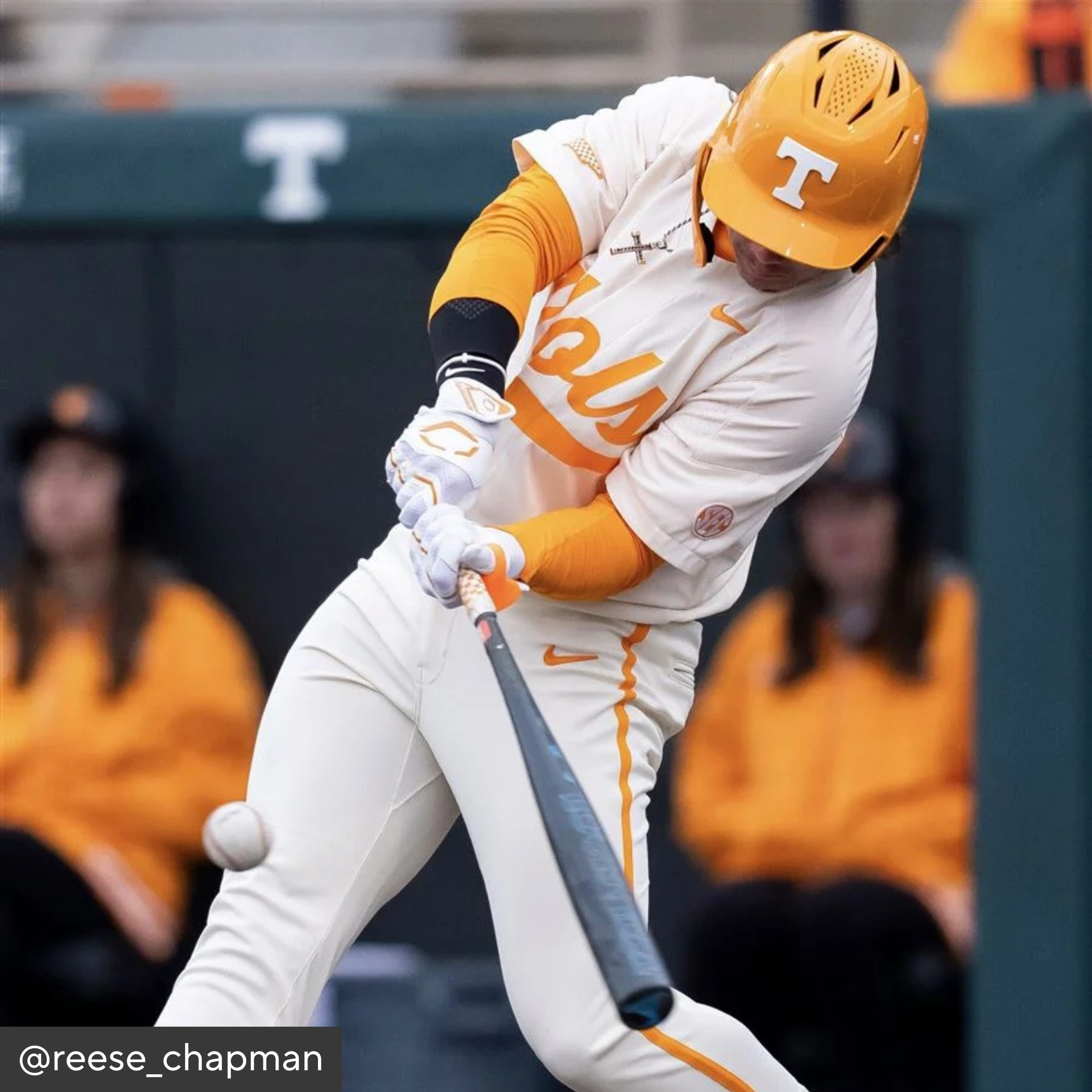 Baseball player in Tennessee uniform swinging a bat with blurred spectators in the background