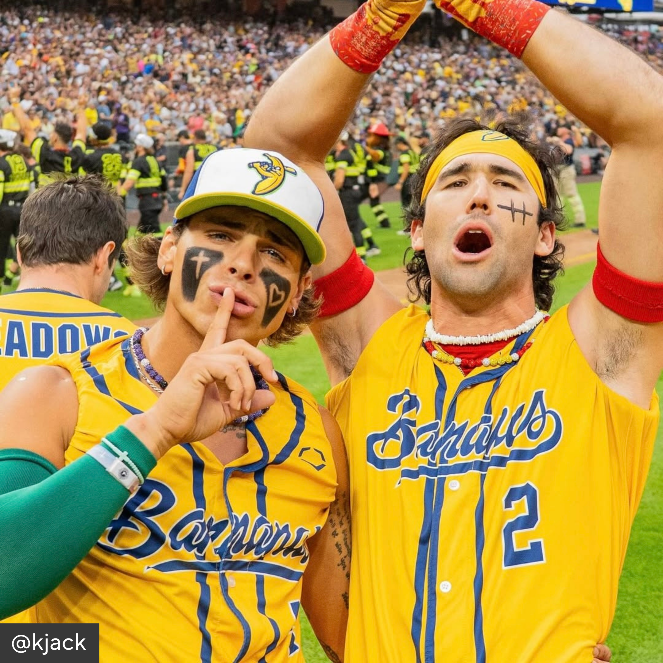 Two men in yellow sports jerseys with face paint and tattoos, one making a &