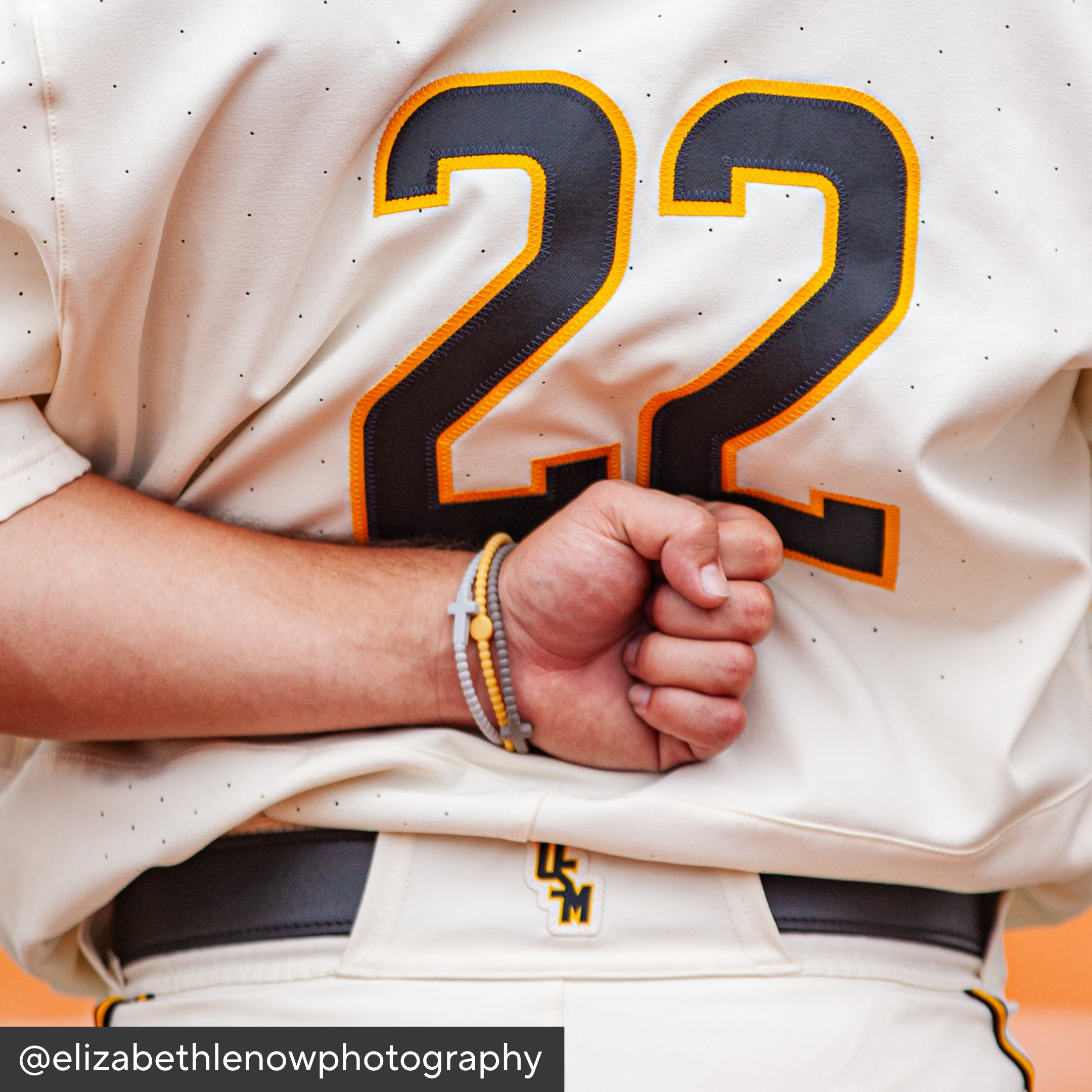Baseball player wearing a jersey with the number 22, clenched fist, and visible brand watermark.
