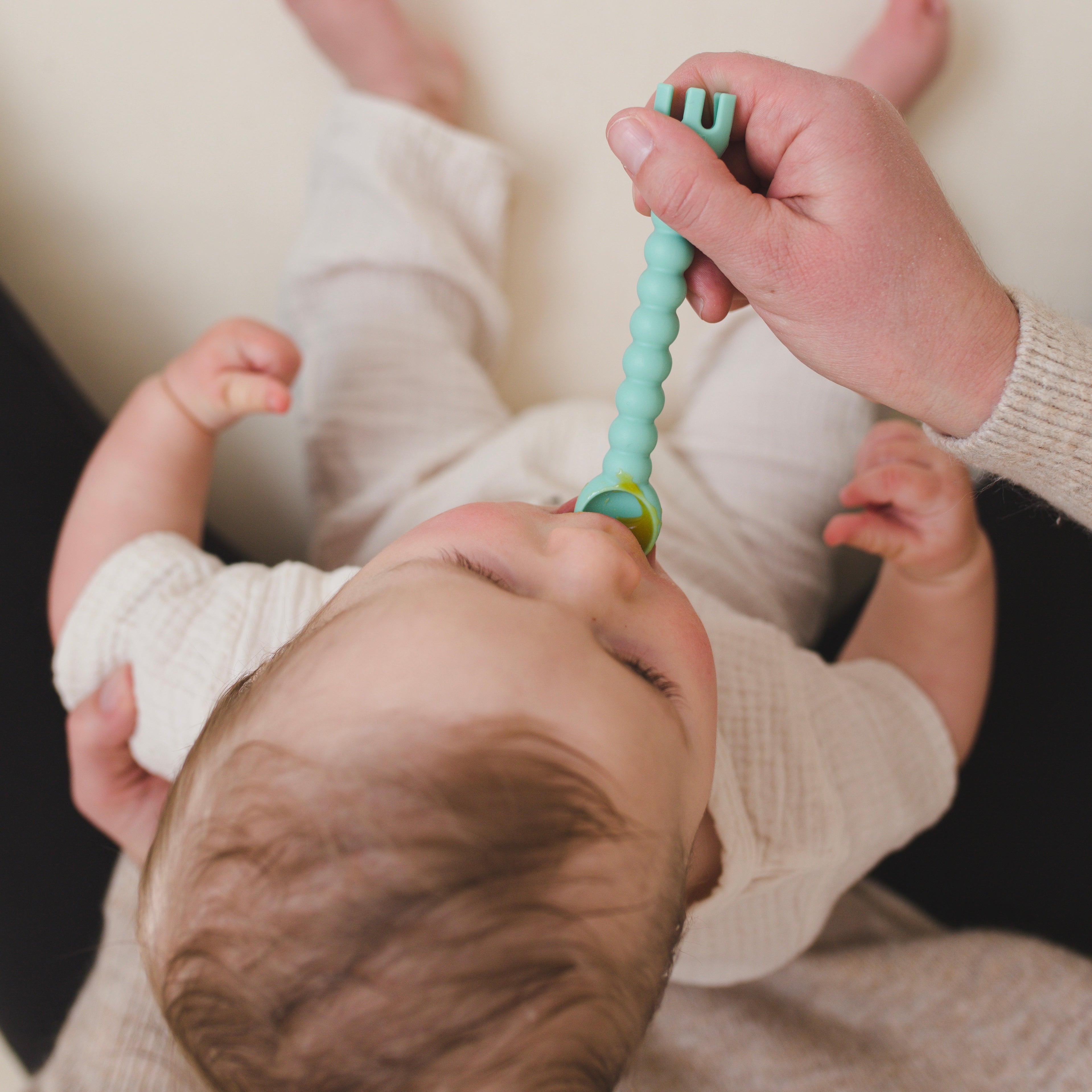 Parent feeding baby with cutie tensil