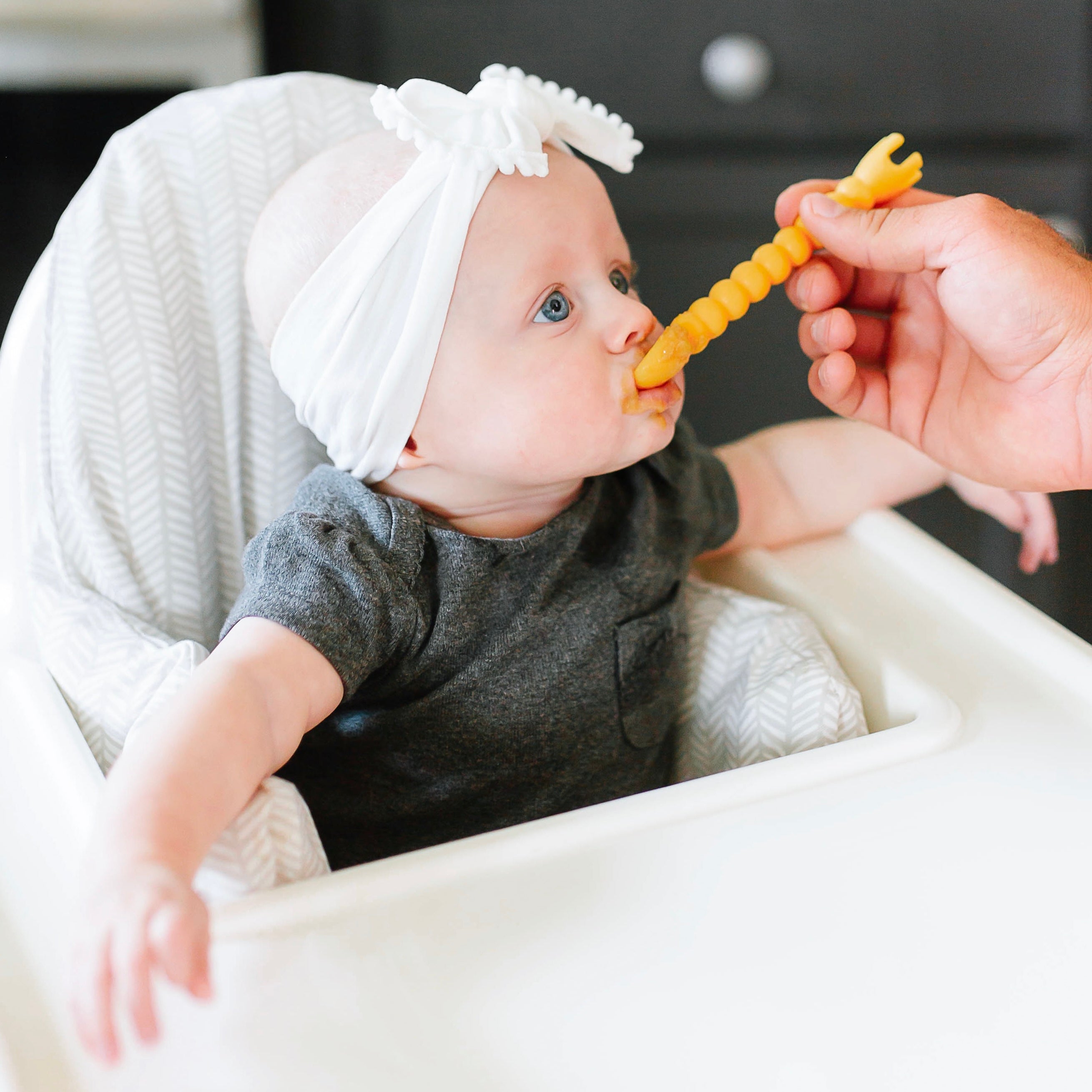 Mom feeding baby with cutie tensils