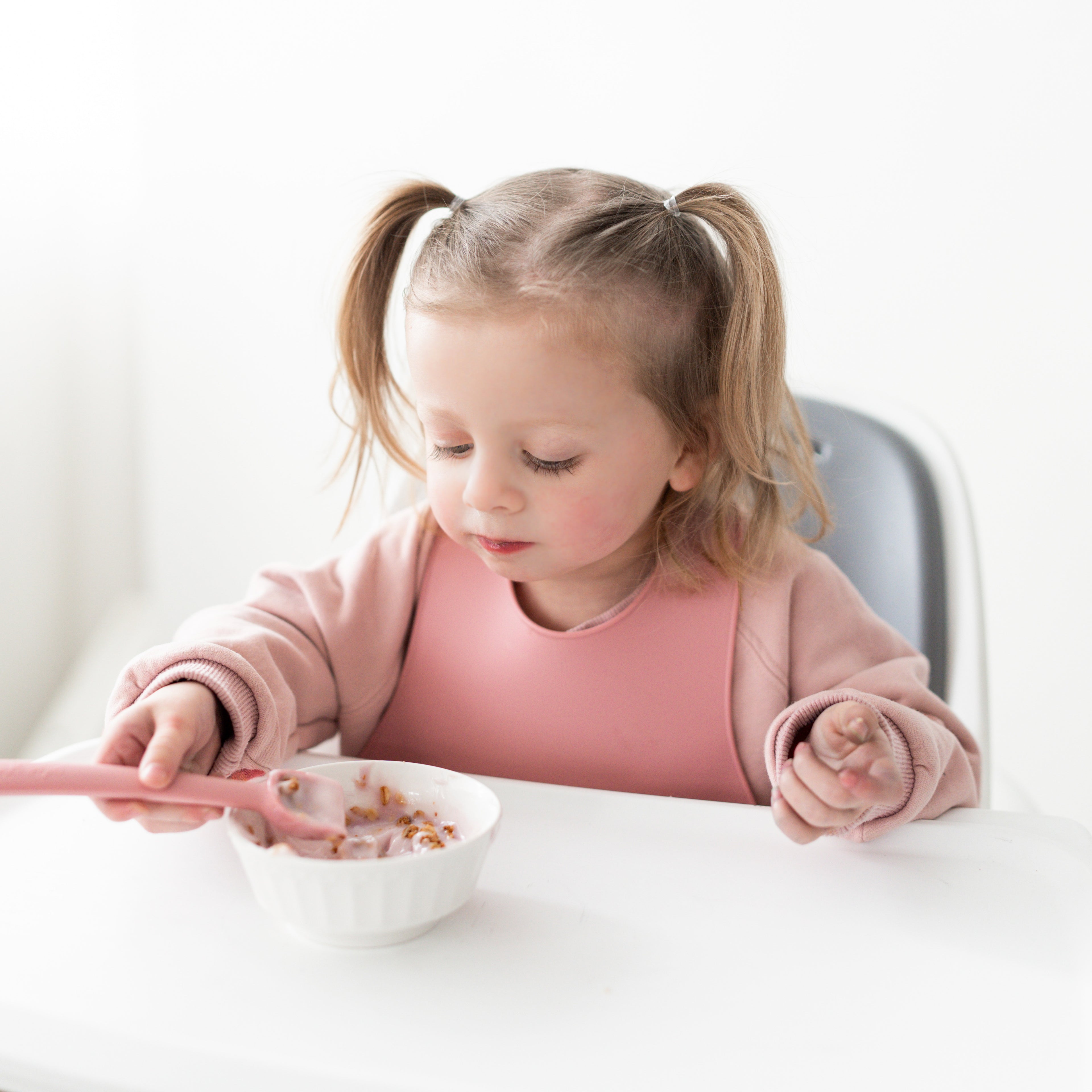 Baby in a high chair eating with Ryan &amp; Rose accessories