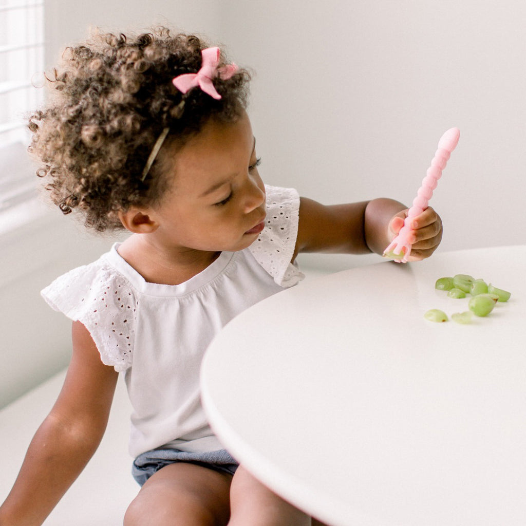 Girl eating grapes using Cutie Tensils.